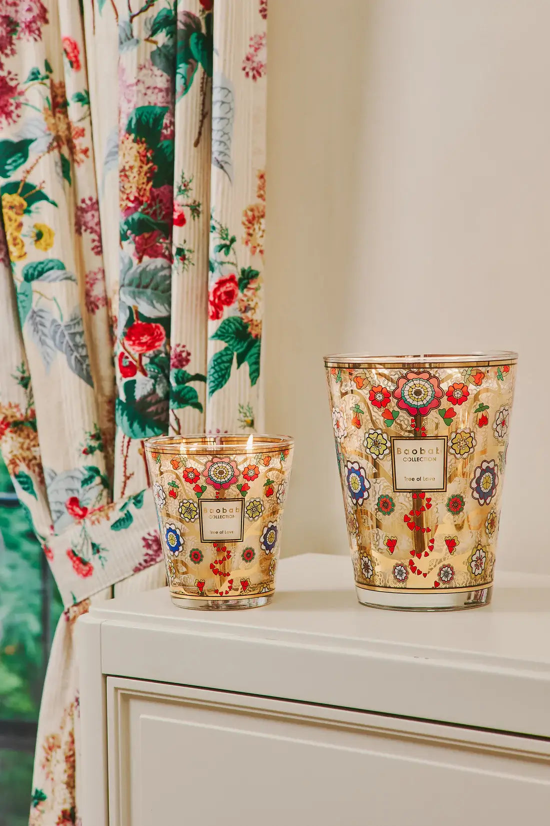 Bougies Baobab Tree of Love max 16, 24 sur une commode dans une pièce blanche décorée d'un rideau fleuri