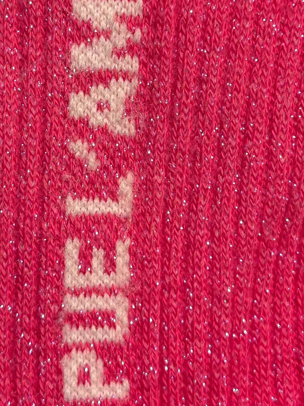Focus sur la chaussette Félicie cousue en coton, rose à paillettes avec « ça pue l'amour » écris en blanc