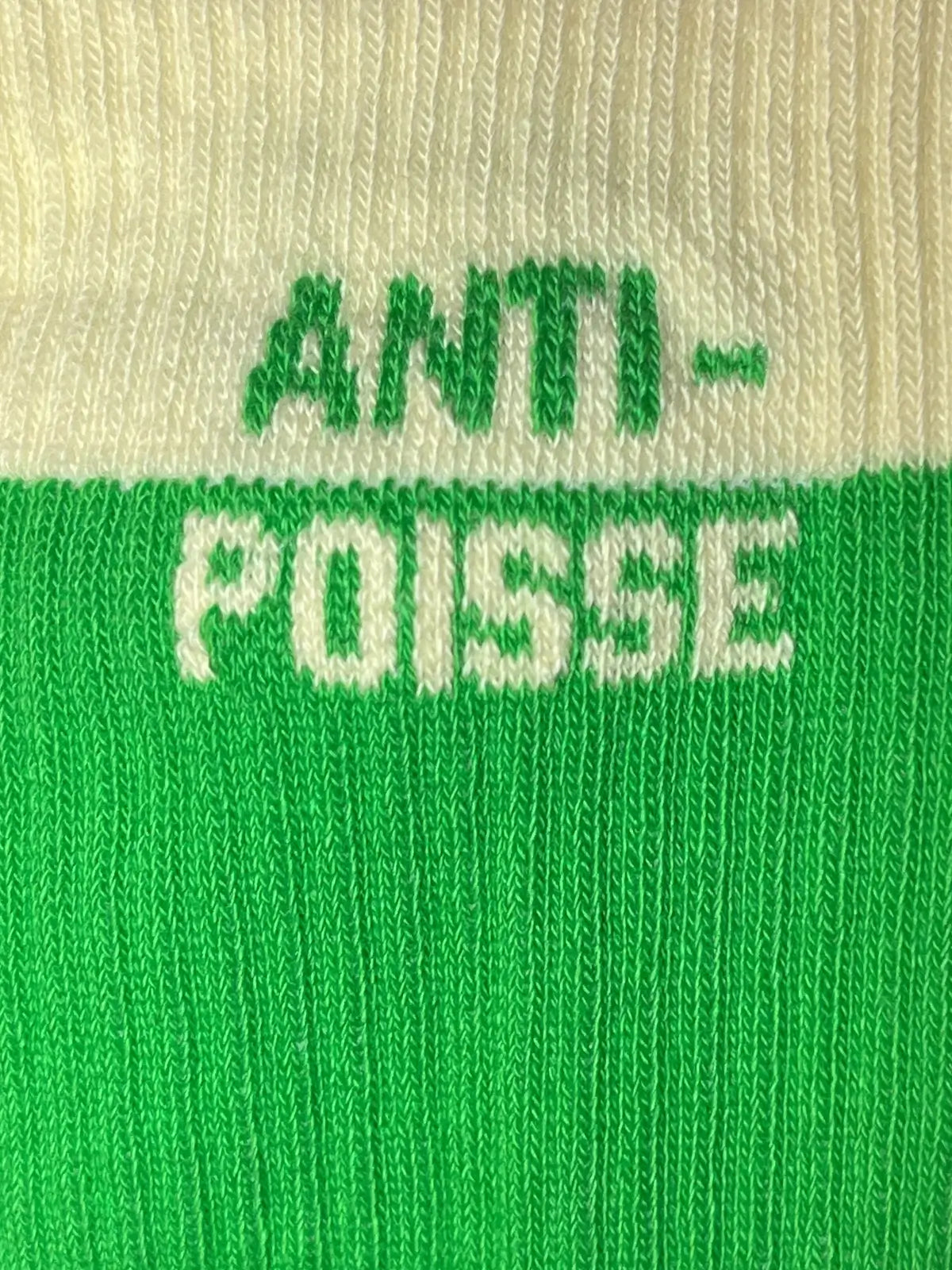 Focus sur la chaussette Félicie cousue en coton, bicolore blanc et vert avec « anti-poisse » écrit en blanc et vert