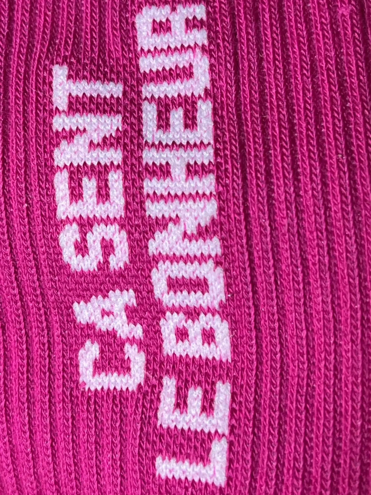 Focus sur la chaussette Félicie cousue en coton, framboise avec « ça sent le bonheur » écrit en blanc