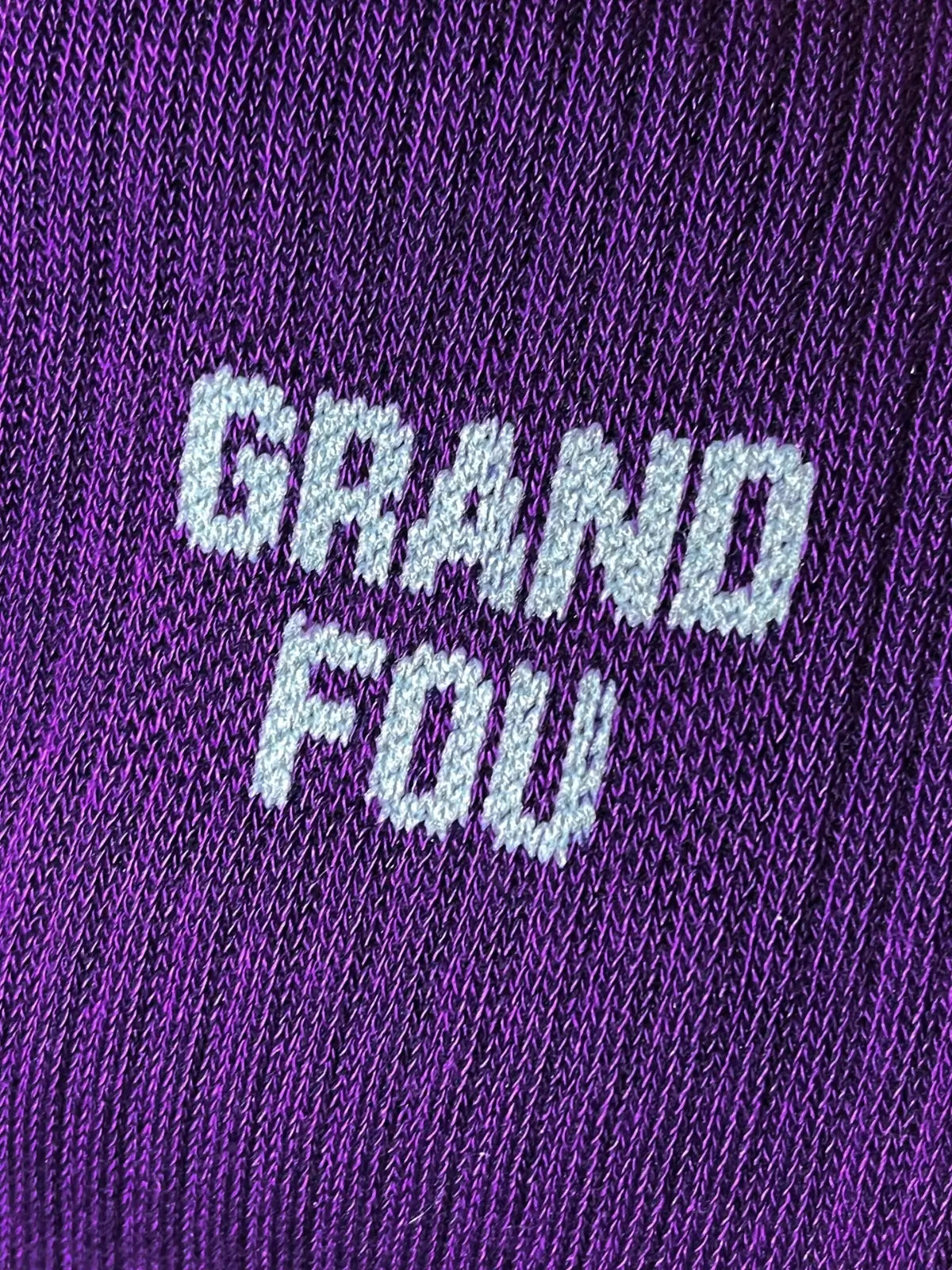 Focus sur la chaussette Félicie cousue en coton, violette à paillettes avec « grand fou » écrit en blanc