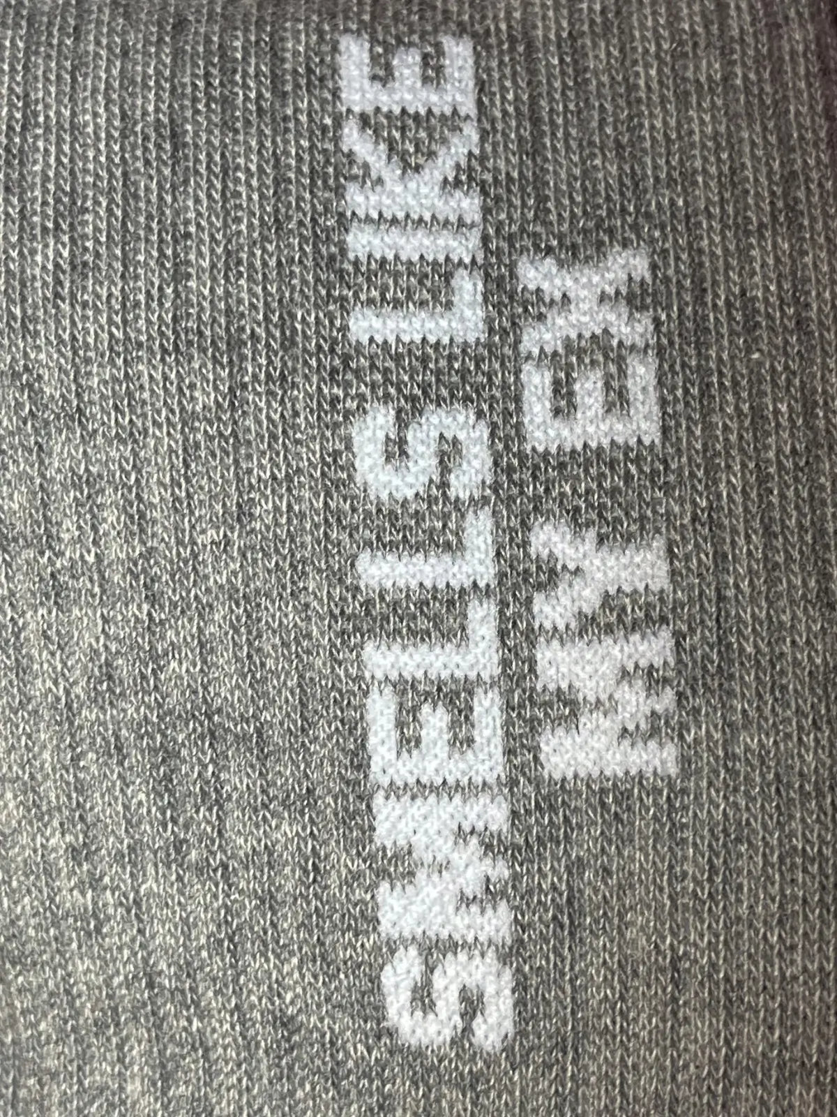 Focus sur la chaussette Félicie cousue en coton, gris avec « smells like my ex » écrit en blanc