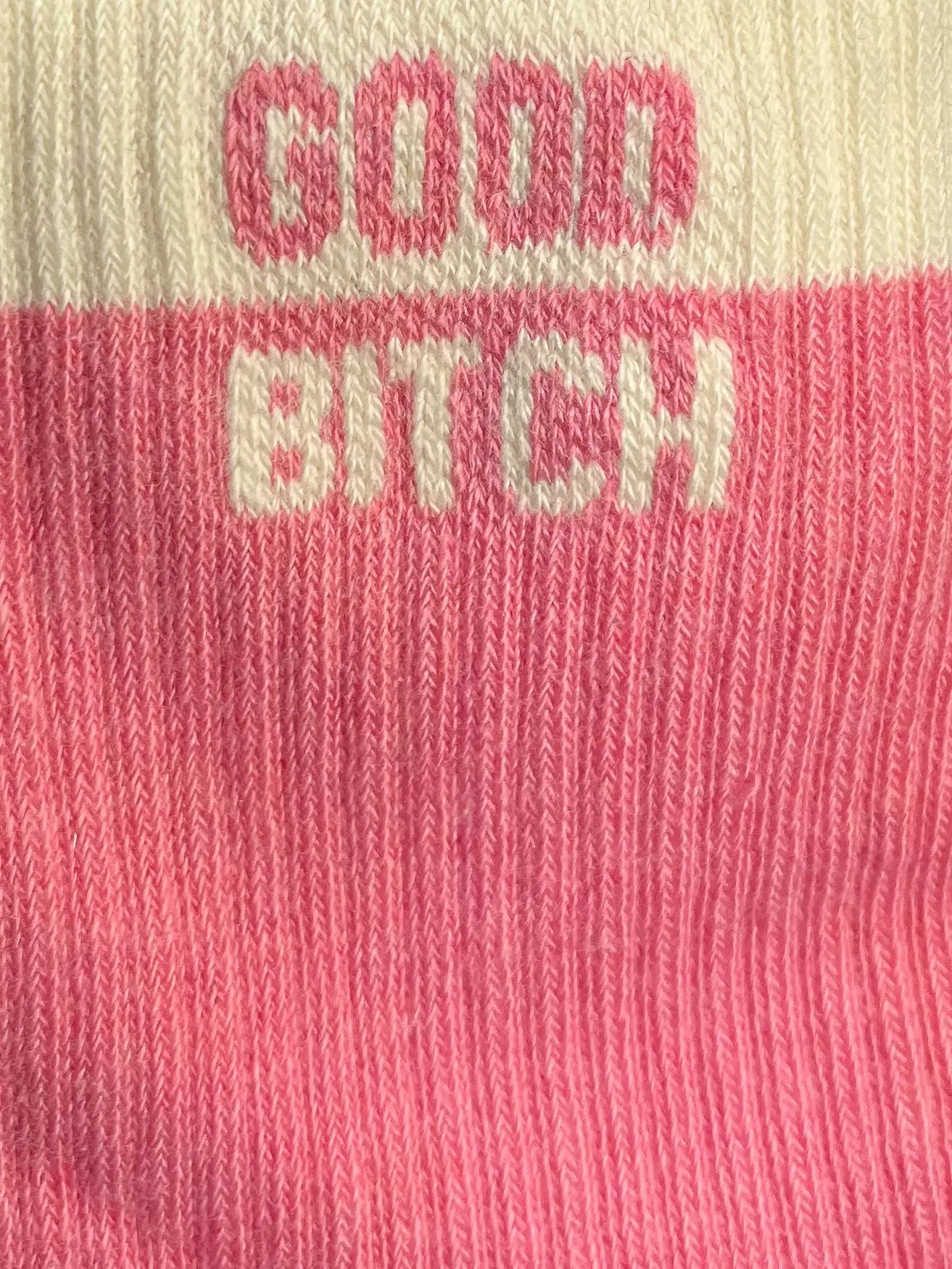Focus sur la chaussette Félicie cousue en coton, couleur rose et blanche avec « Good Bitch » écris en blanc et rose