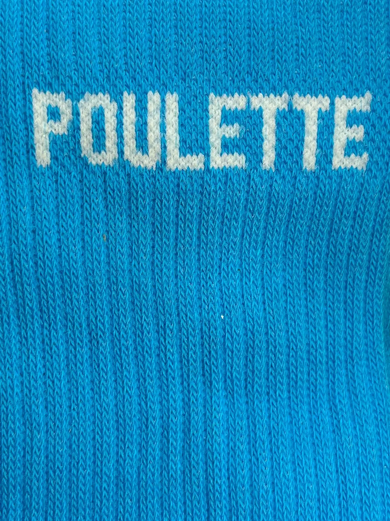 Focus sur la chaussette Félicie cousue en coton, bleue avec « Poulette » écris en blanc