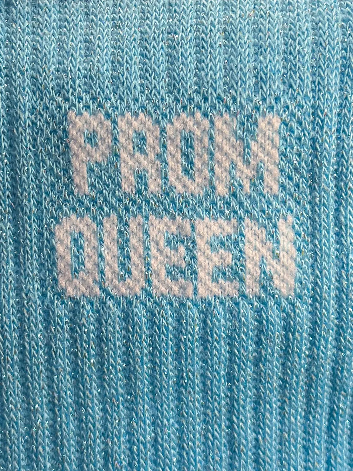 Focus sur la chaussette Félicie cousue en coton, bleue ciel à paillettes avec « Prom Queen » écris en blanc