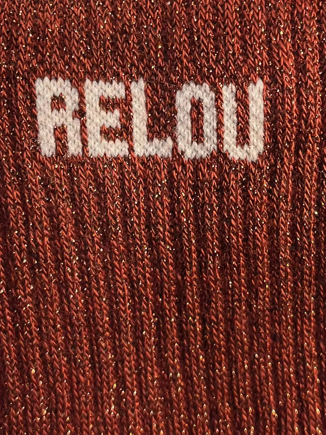 Focus sur la chaussette Félicie cousue en coton, couleur rouille à paillettes avec « Relou » écris en blanc