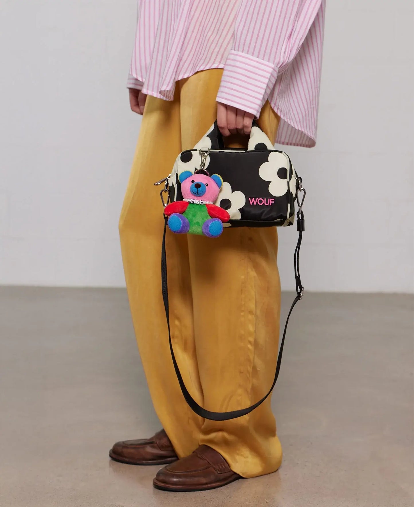 Porte-clés Rainbow Bear Charm de chez Wouf accroché à un sac noir à fleurs blanches