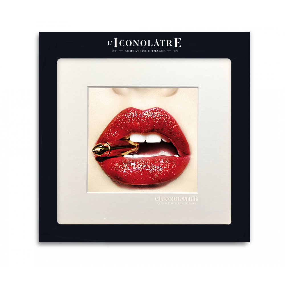 Photographie 22x22 d'une bouche de femme avec du rouge lèvre rouge tenant une balle dorée entre les dents par Image Républic