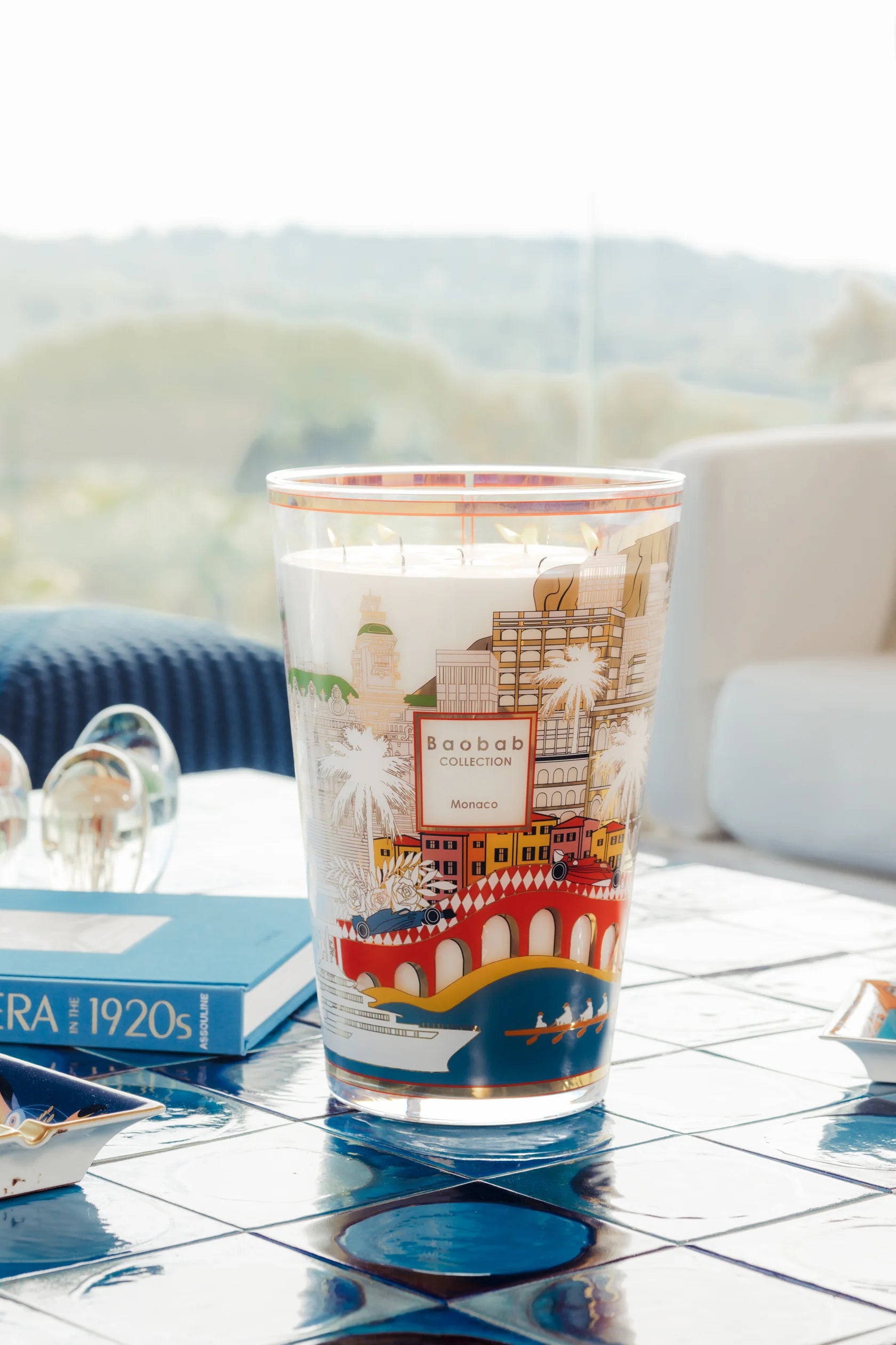 Bougie Monaco Baobab Collection Max 35 sur table bleue devant fenêtre