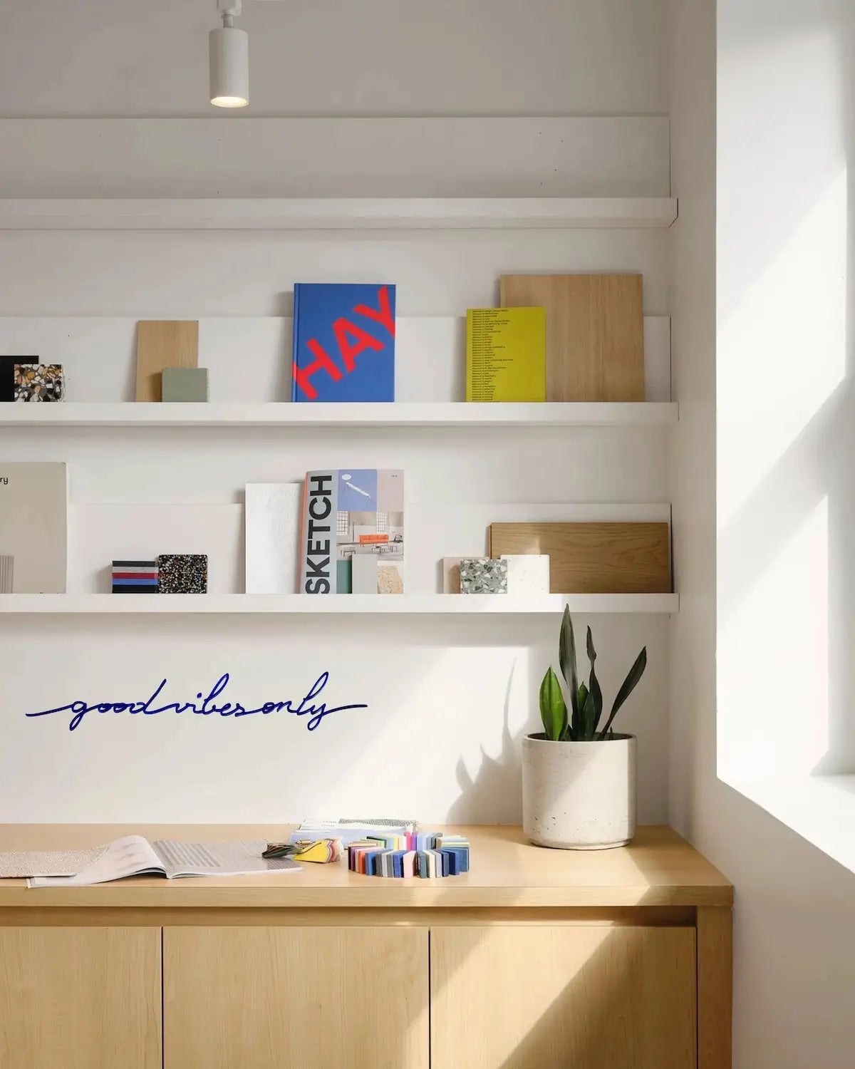 Phrase murale "Good Vibes Only" bleue dans une bibliothèque