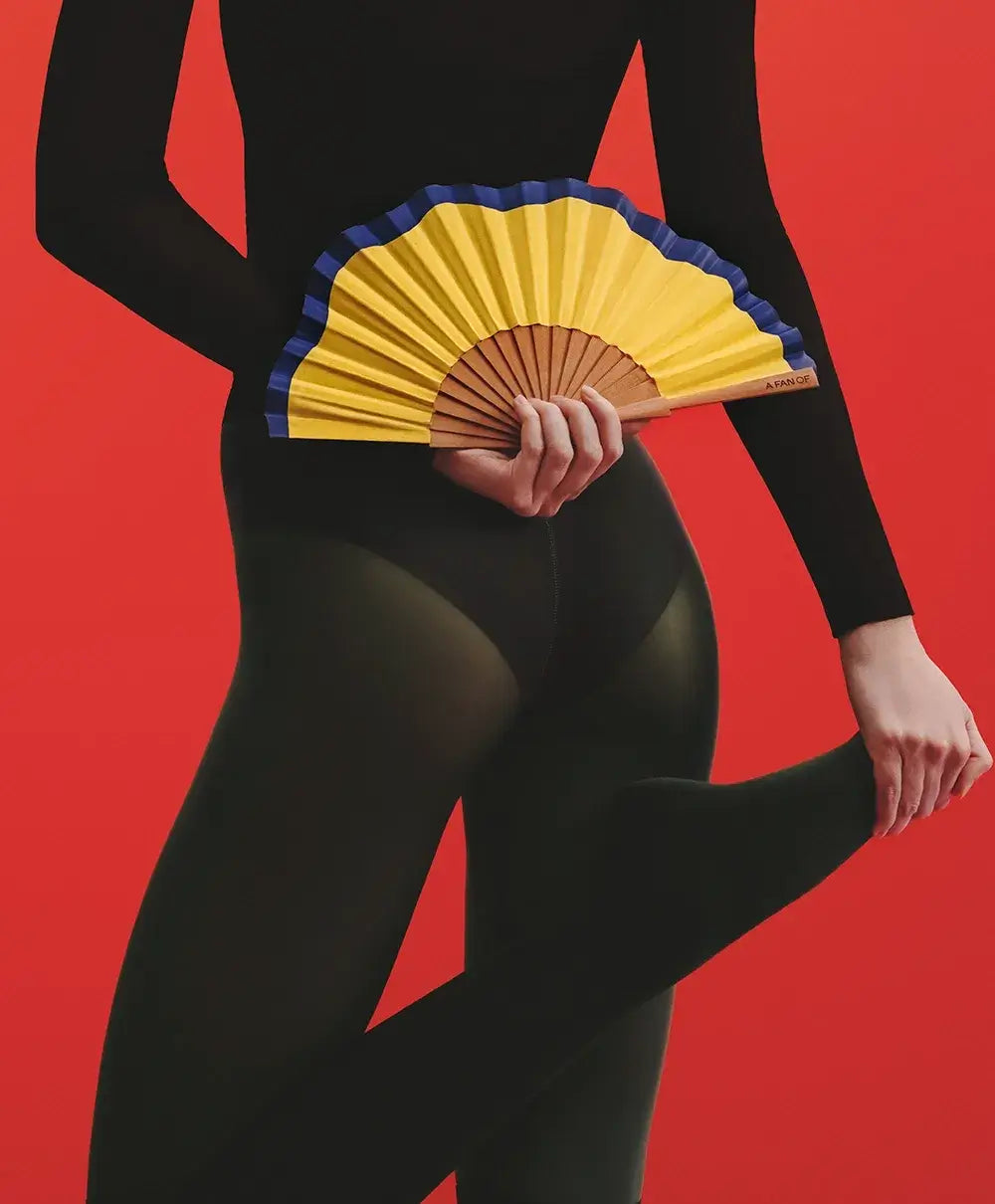 Éventail A Fan Of Fluid Shapes Jaune tenu par une danseuse