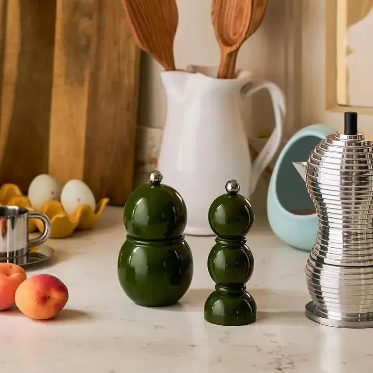 Bobbin Kaki placé sur un plan travail entre les ustensiles de cuisine et des fruits
