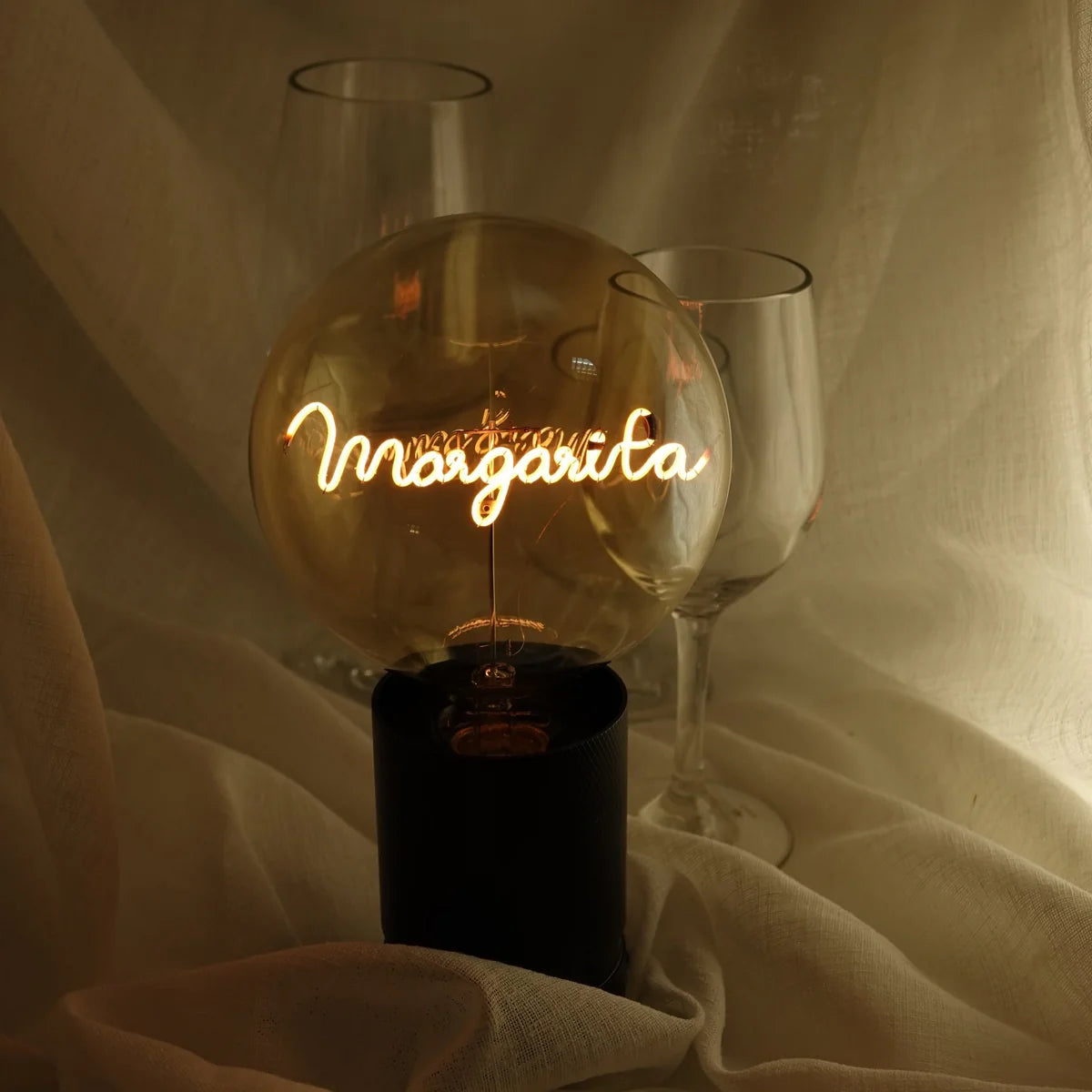 Ampoule Message in the bulb avec le mot Margarita écrit dans un style manuscrit qui s'illumine. Présentation lifestyle avec 2 verres