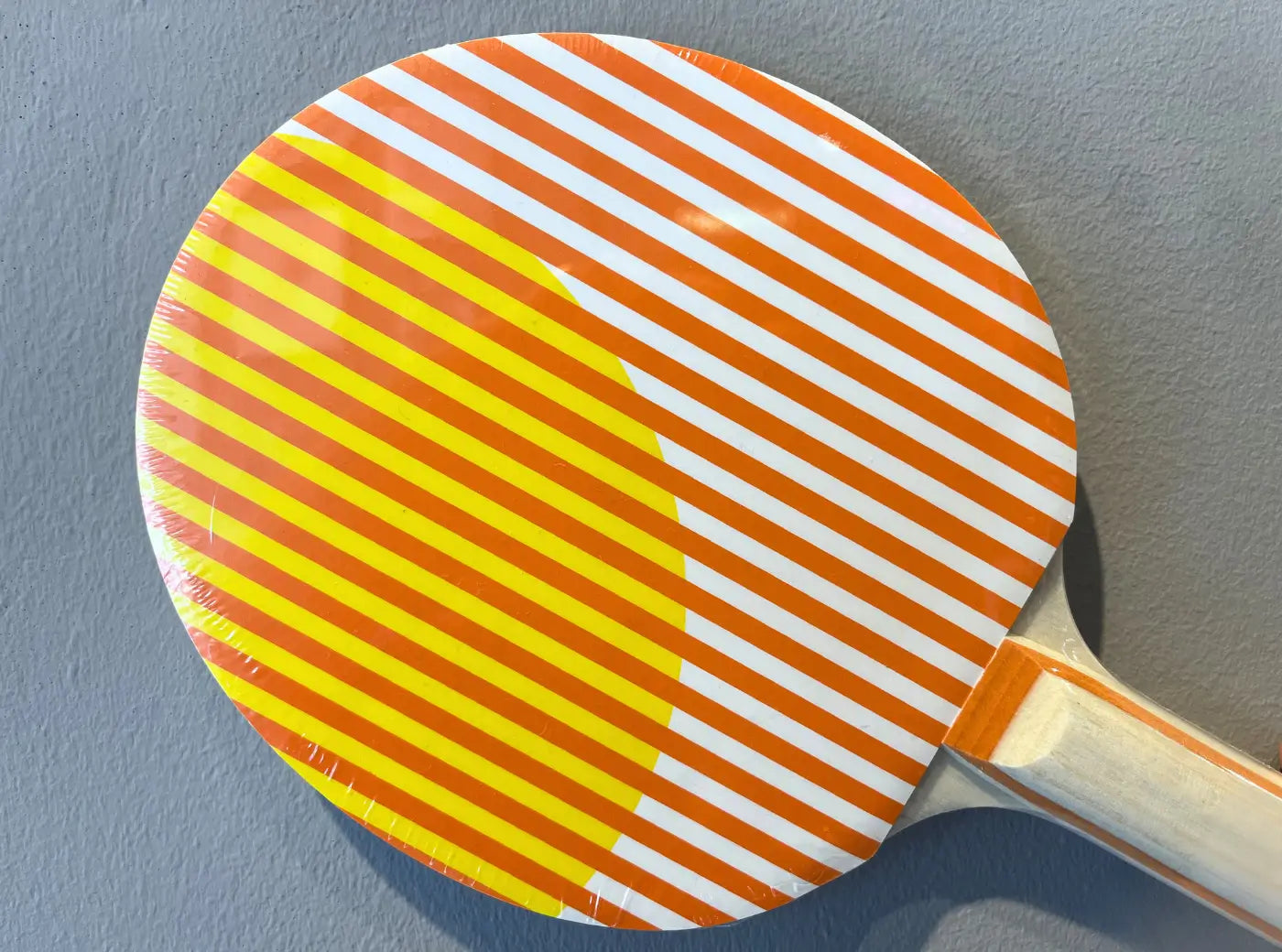 Détail de la raquette de ping-pong Heatwave Art of Ping Pong avec motif graphique rayé orange et jaune