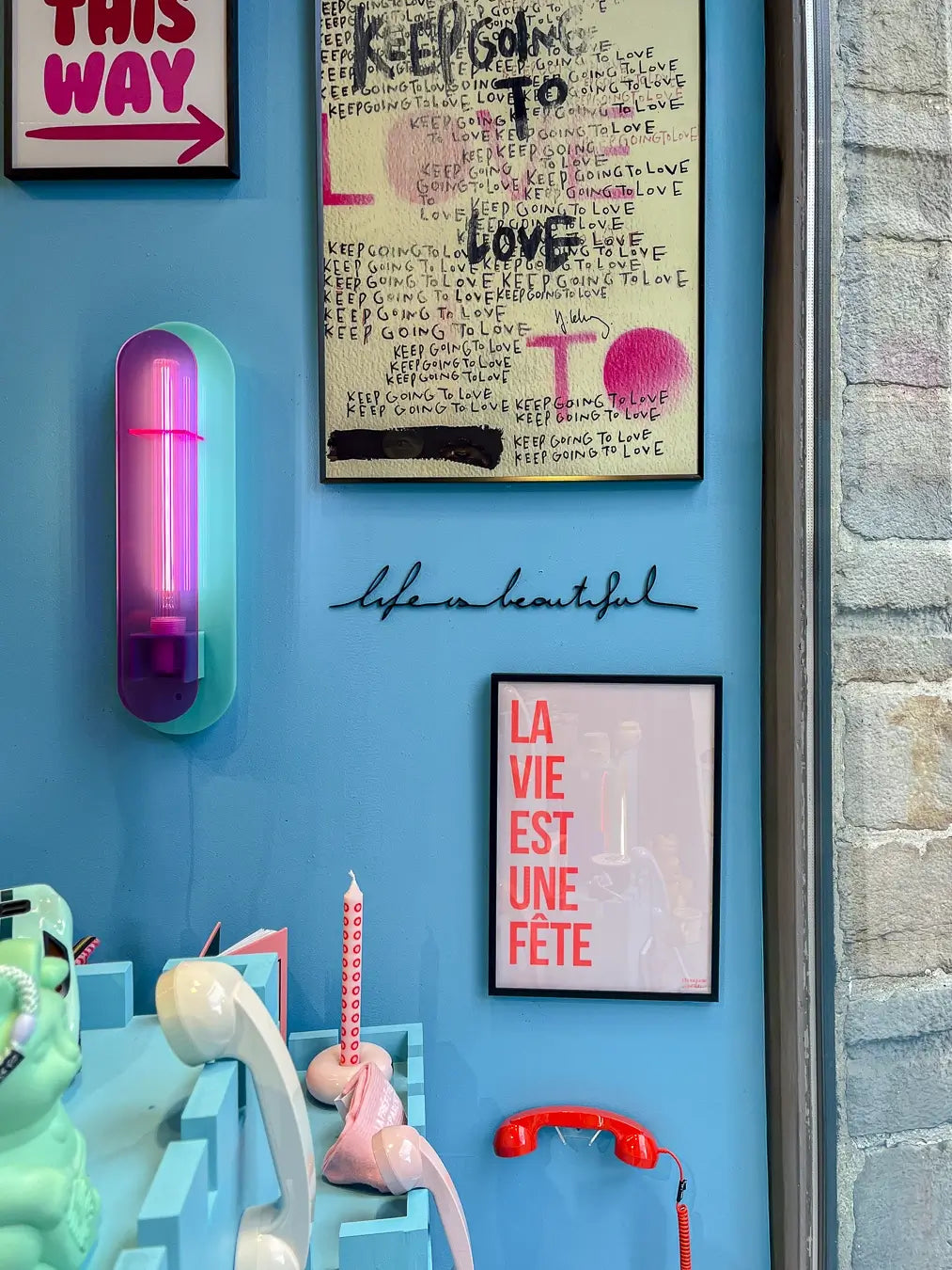 Applique murale "Life is beautiful" par Atelier Suspendu au milieu d'un composition colorée, majoritairement bleue et rose