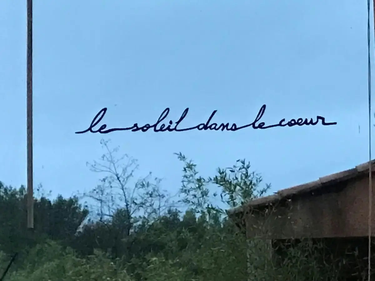 Phrase murale "Le Soleil dans le cœur" noire sur une fenêtre
