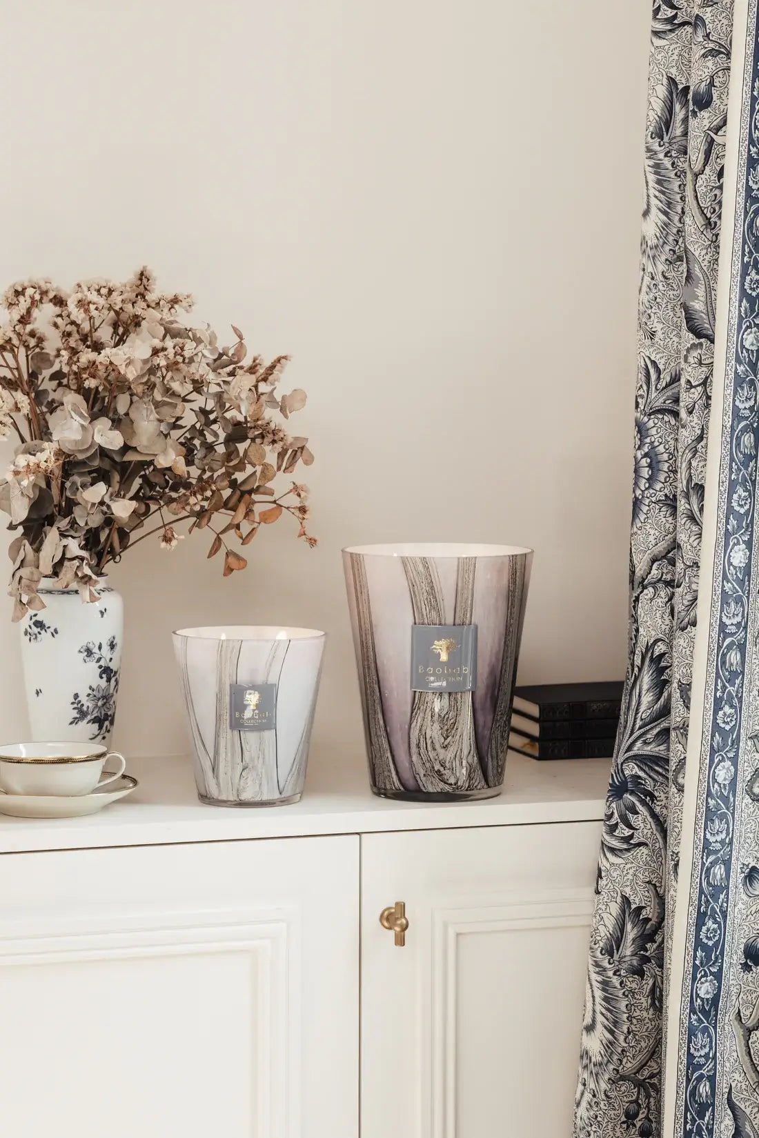 Deux bougies Brocéliande de la collection Woods (taille 16 et 24) sur la commode d'un salon blanc