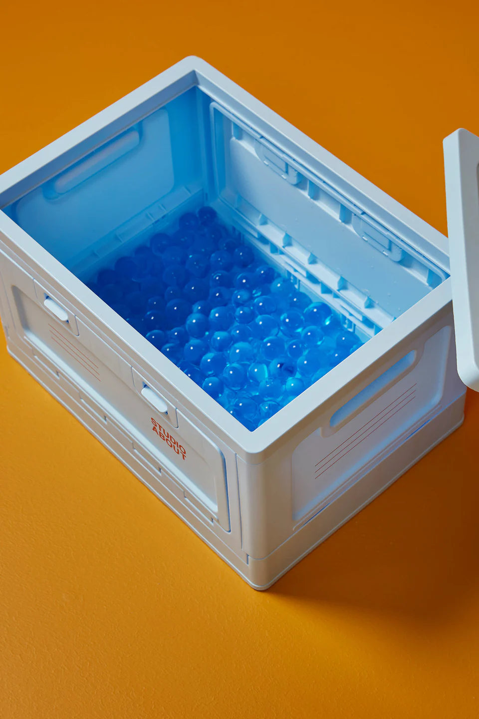 Vue plongeante sur l'intérieur de la boite de rangement bleu clair Studio About, nous laissant observer son ouverture par le dessus à la manière d'une caisse de rangement