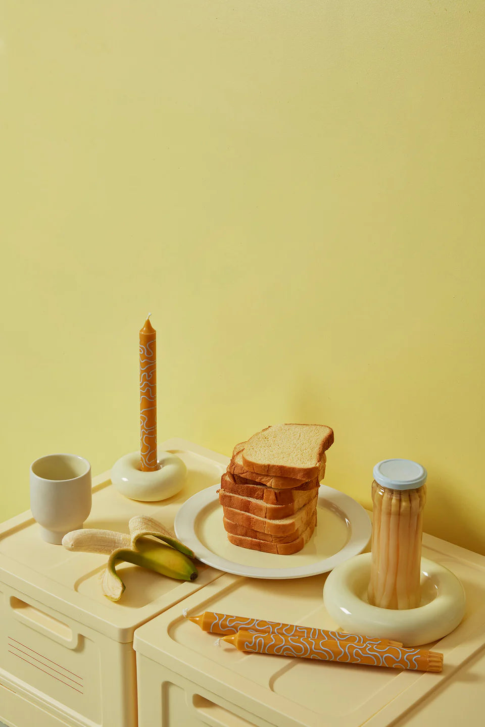 Boite de rangement jaune Studio About avec de la vaisselle, de la nourriture, des bougeoirs et des bougies.