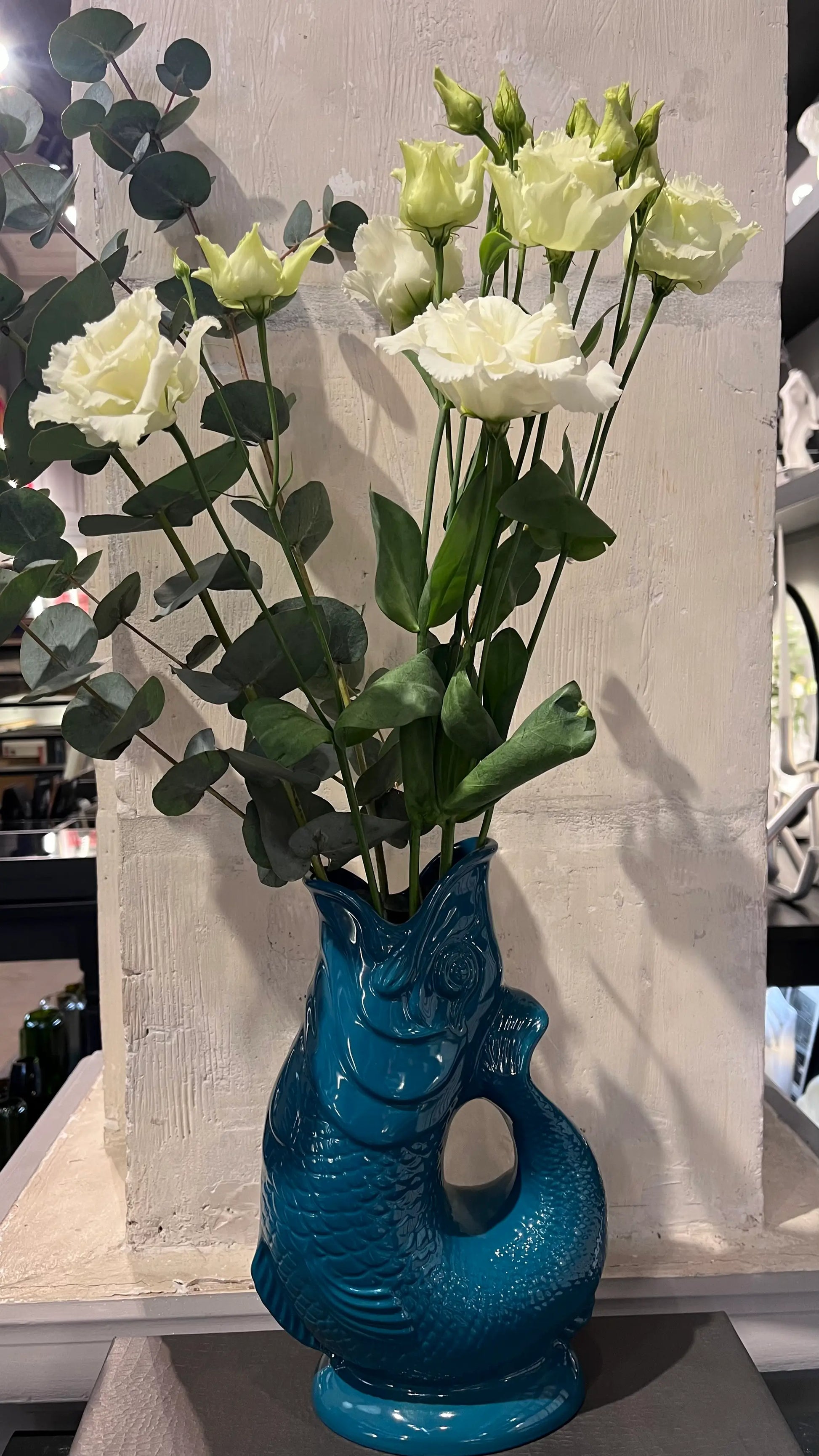 Vase Glouglou pétrole avec des fleurs, devant un pilier en pierre 