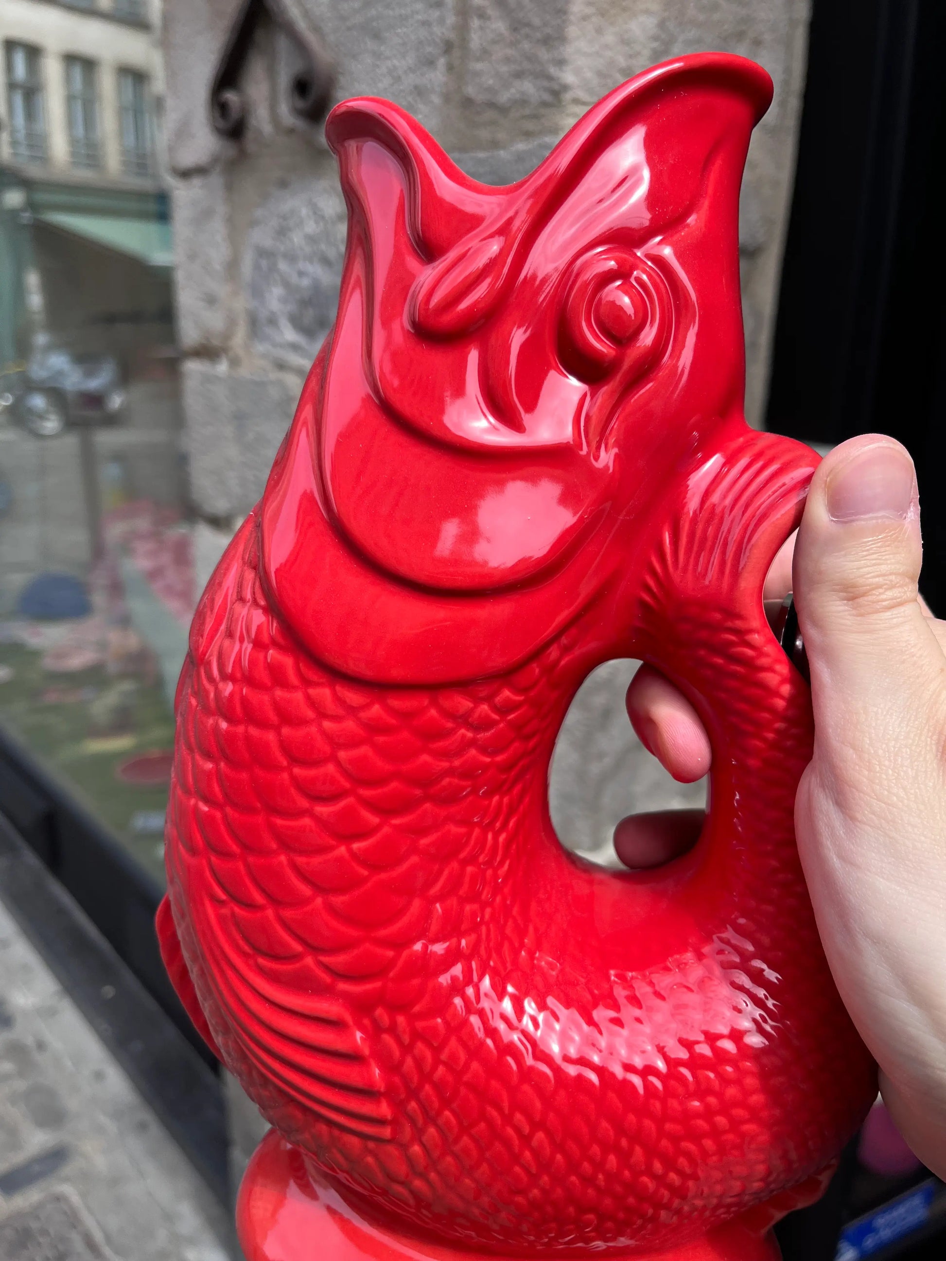 Carafe Glouglou rouge devant un mur en pierre 