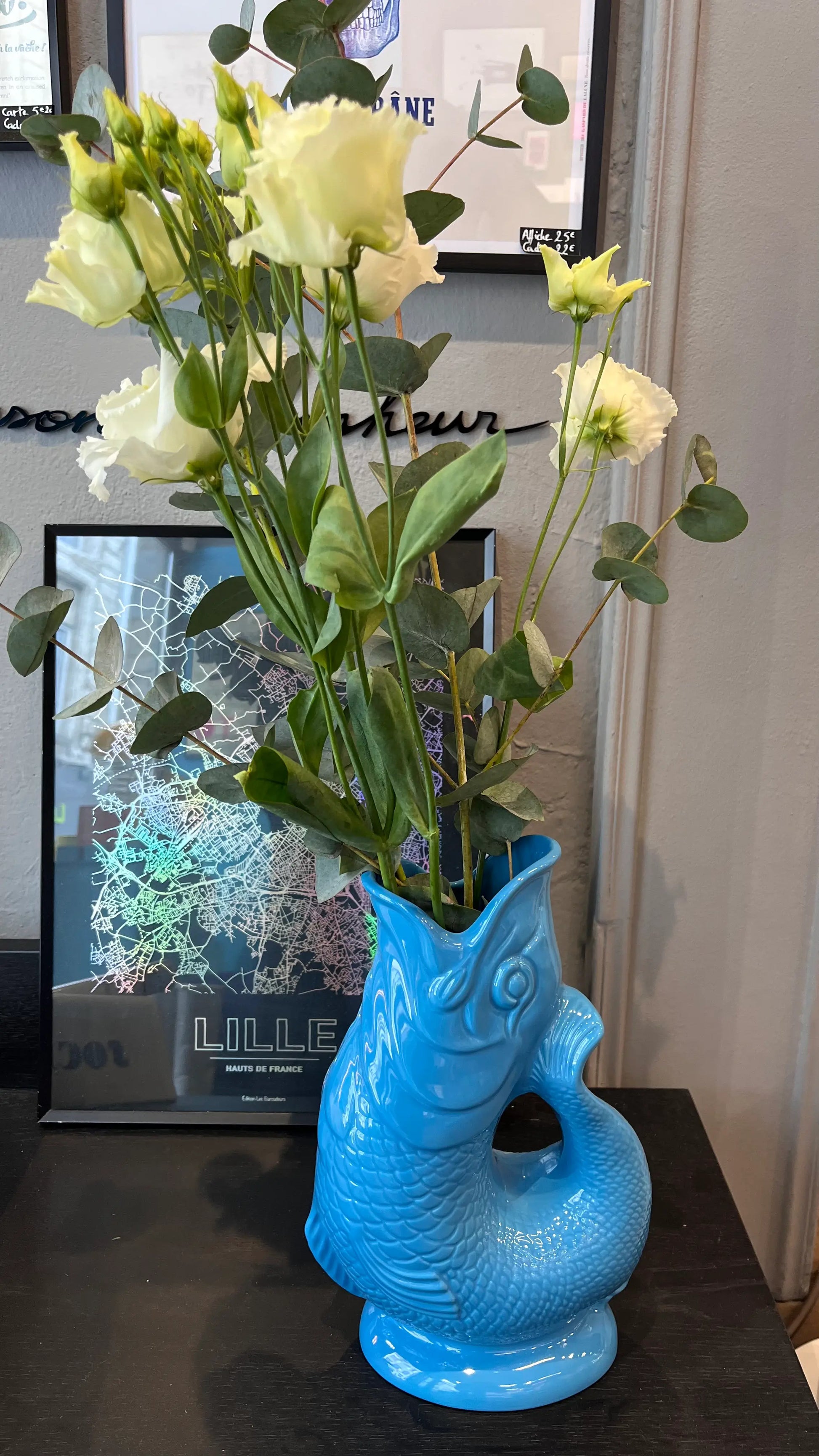 Vase Glouglou turquoise avec des fleurs sur une étagère