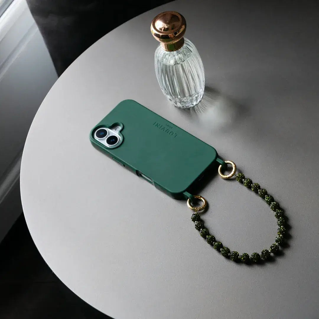 iPhone équipé d'une coque Milo vert et d'un bracelet, posé sur une table