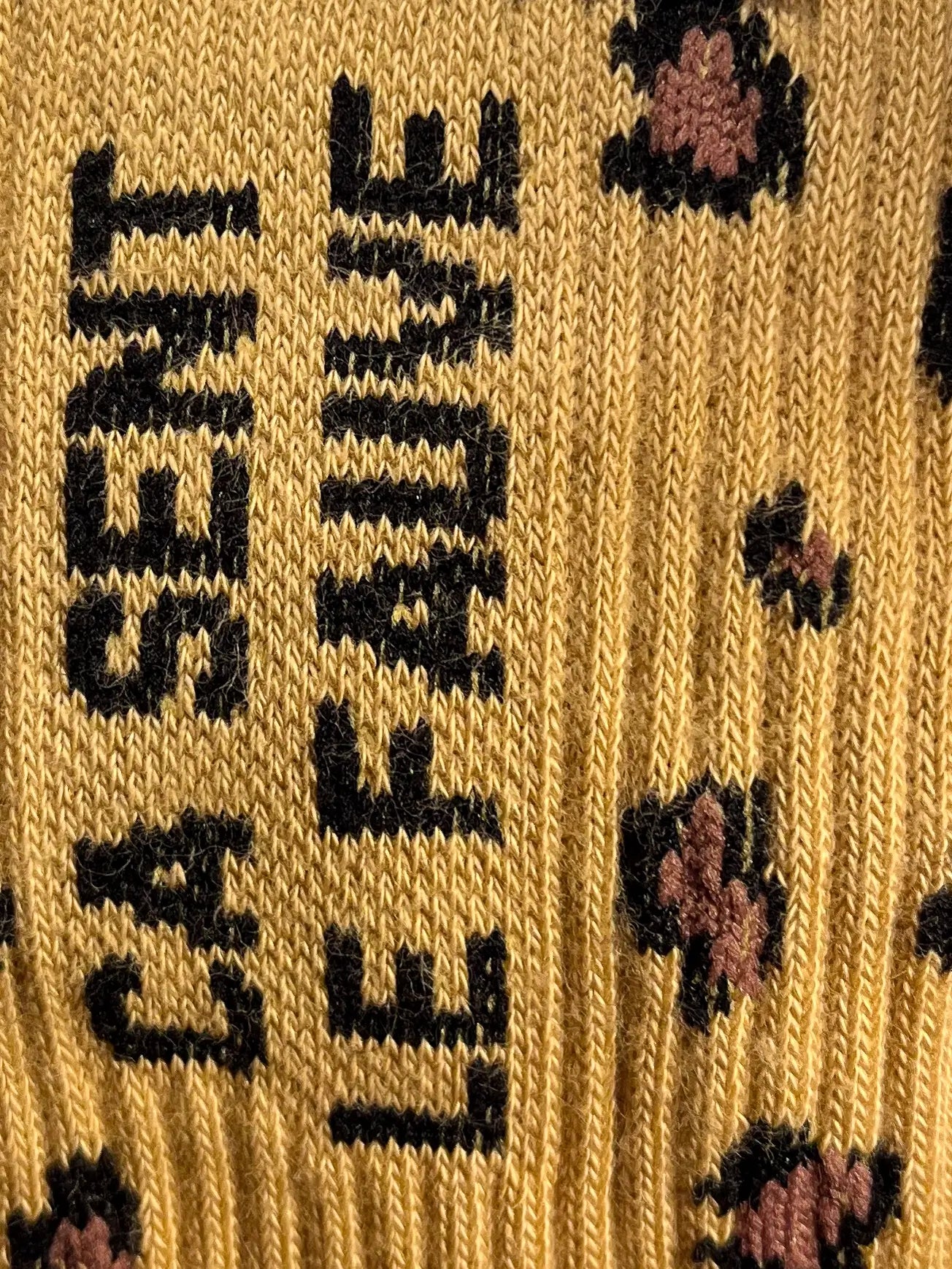 Focus sur la chaussette Félicie cousue en coton, motif léopard avec « ça sent le fauve » écris en noir