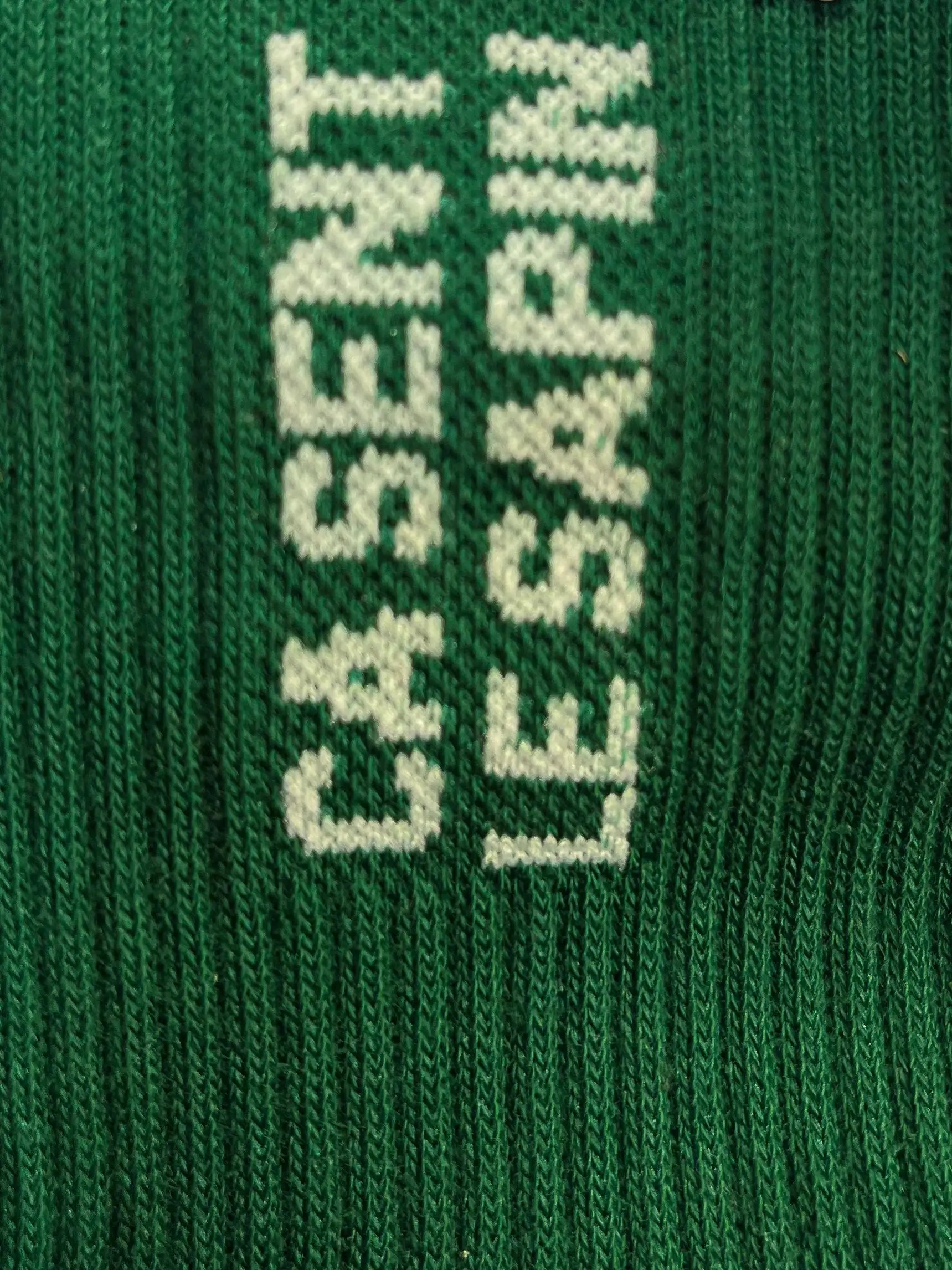 Focus sur la chaussette Félicie cousue en coton, vert avec « ça sent le sapin » écris en blanc