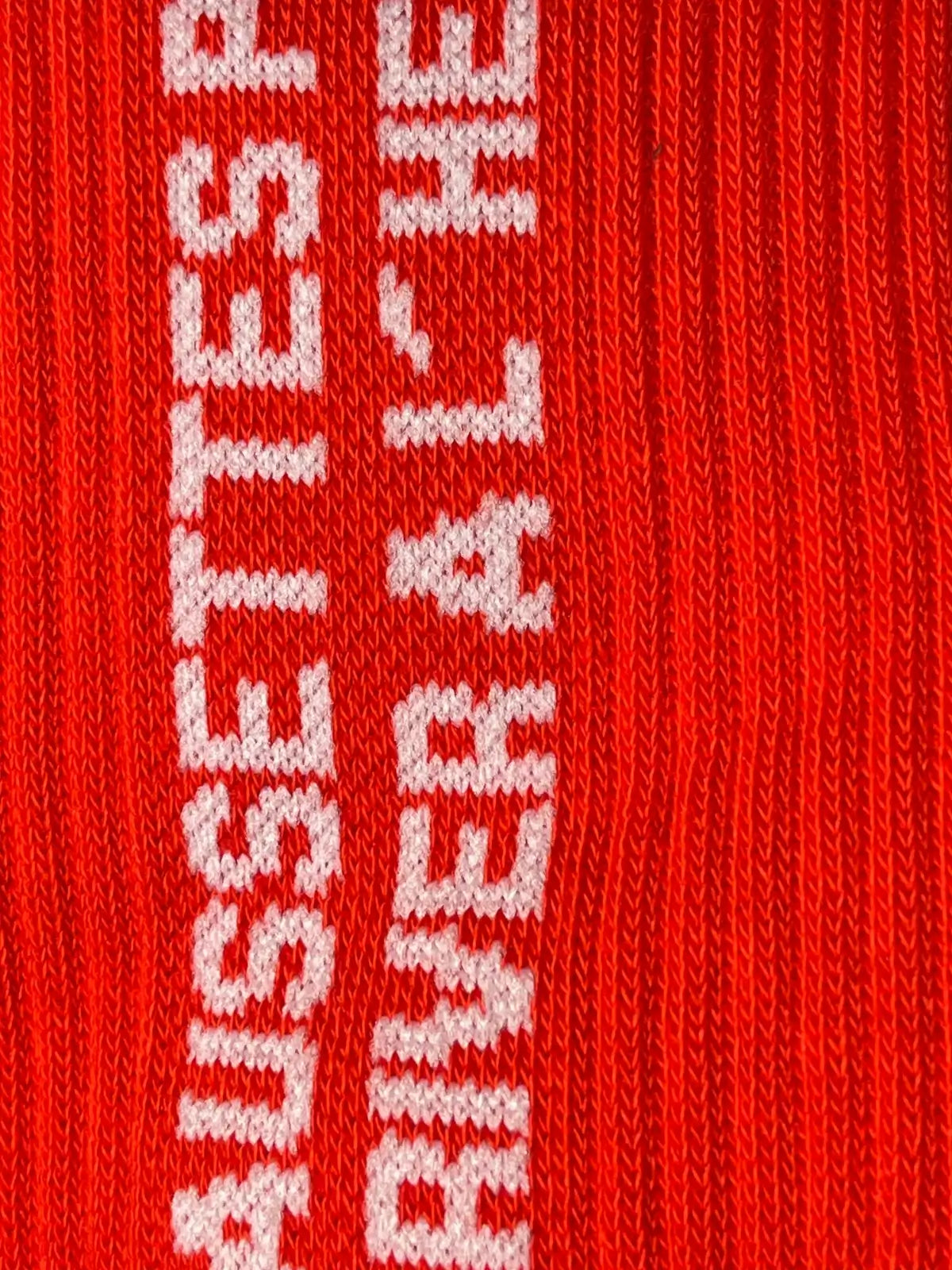 Focus sur la chaussette Félicie cousue en coton, rouge avec « chaussettes pour arriver àl'heure » écrit en blanc