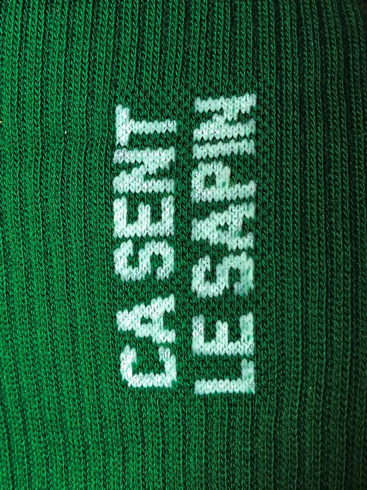 Focus sur la chaussette Félicie cousue en coton, vert avec « ça sent le sapin » écrit en blanc