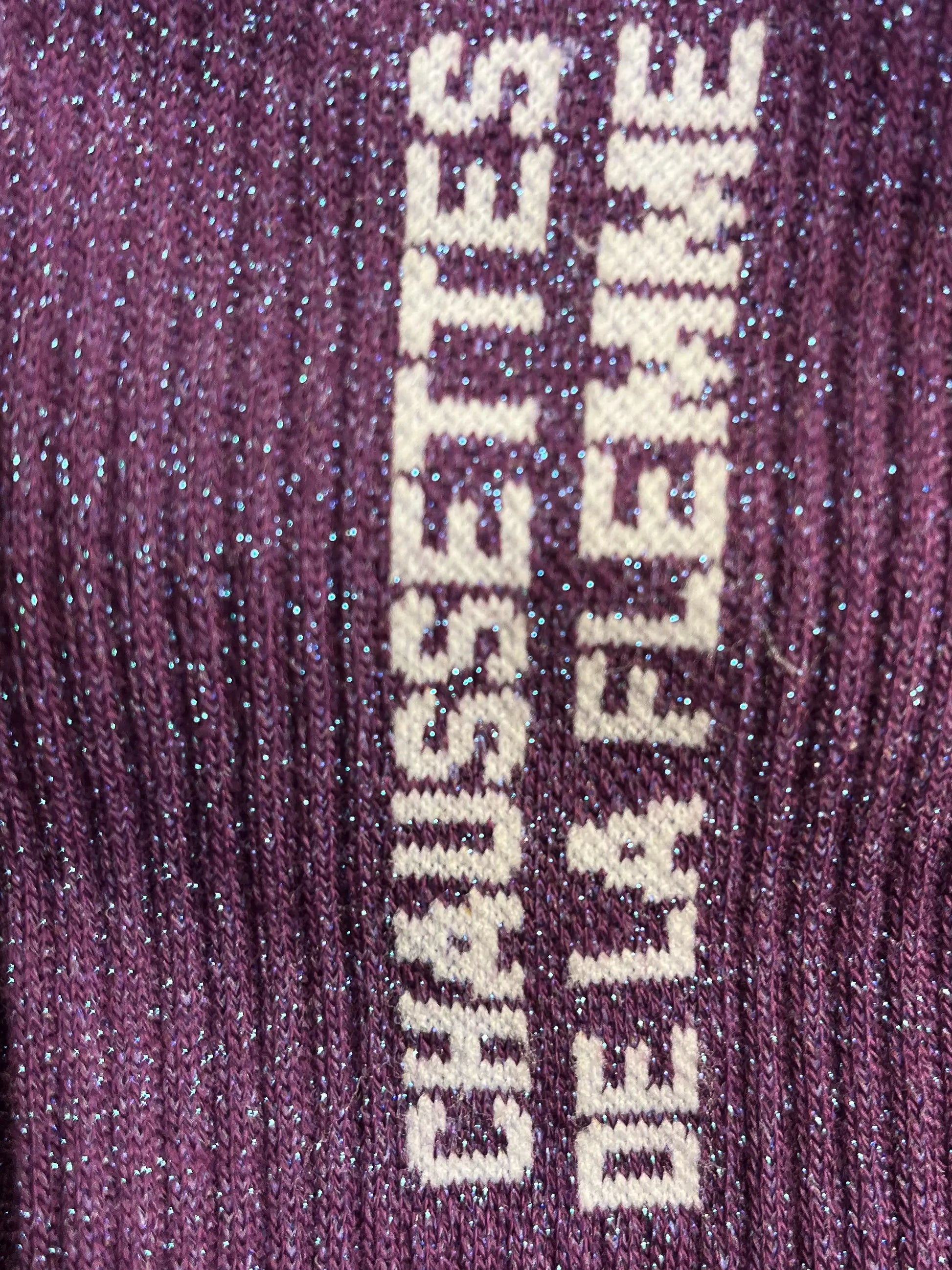 Focus sur la chaussette Félicie cousue en coton, violette à paillettes avec « Chaussettes de la flemme » écris en blanc