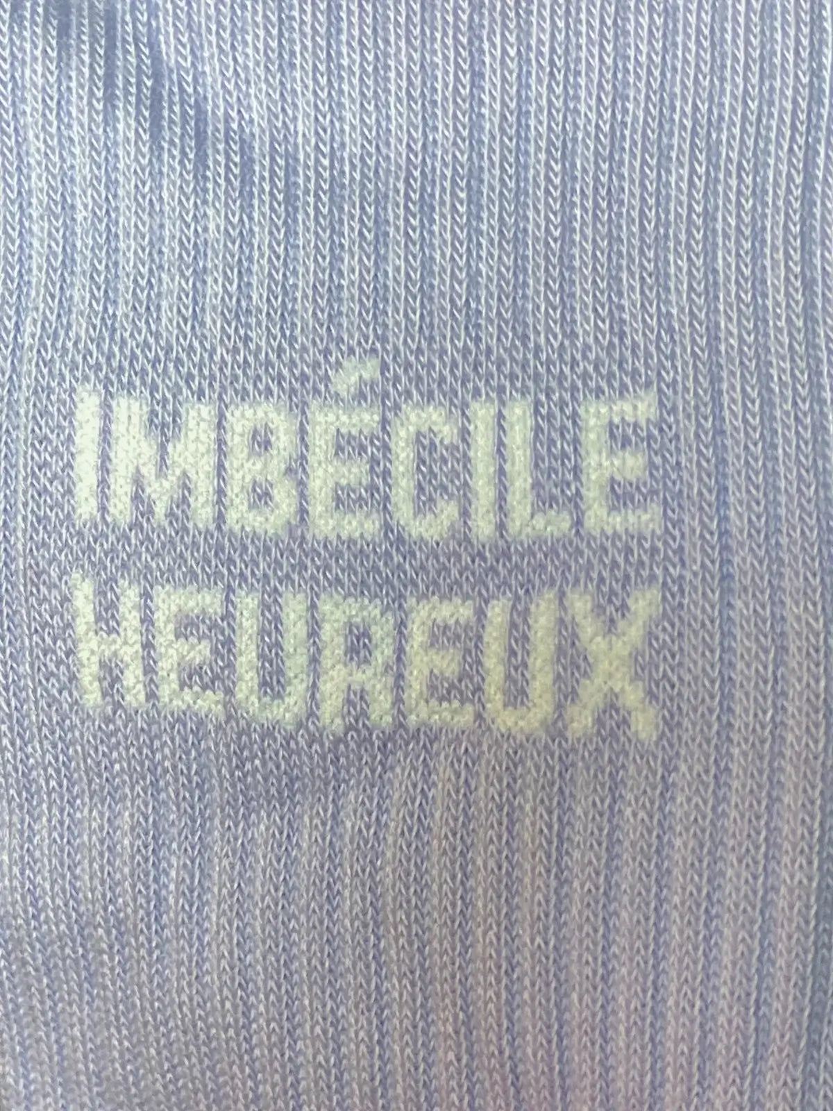 Focus sur la chaussette Félicie cousue en coton, mauve avec « imbécile heureux » écrit en blanc