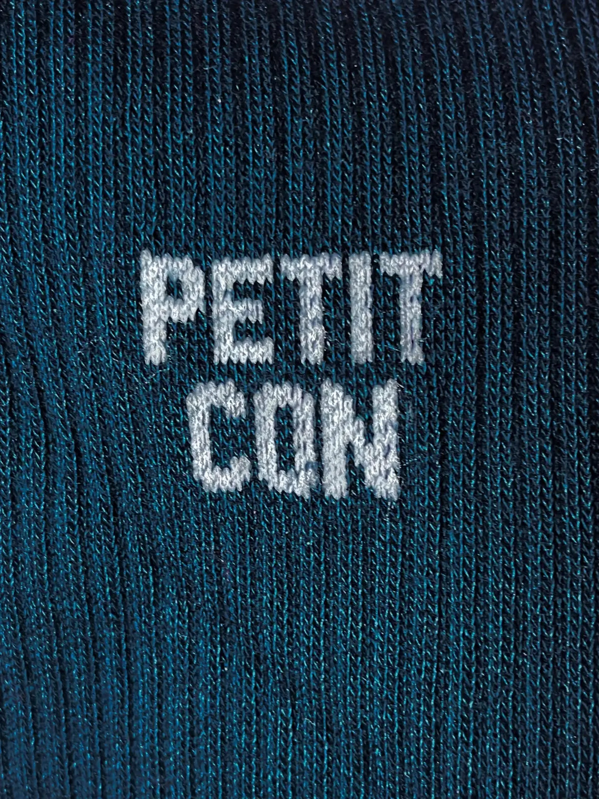 Focus sur la chaussette Félicie cousue en coton, bleu marine avec « petit con » écrit en blanc