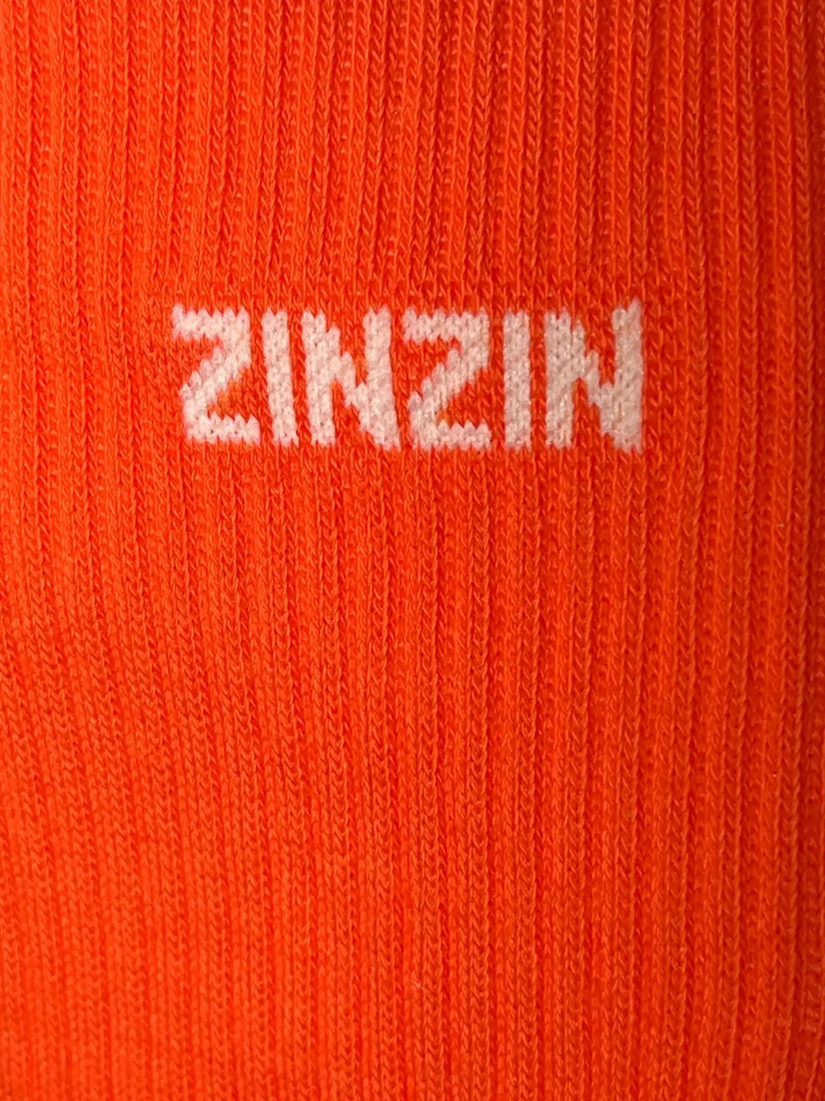 Focus sur la chaussette Félicie cousue en coton, orange avec « zinzin » écrit en blanc
