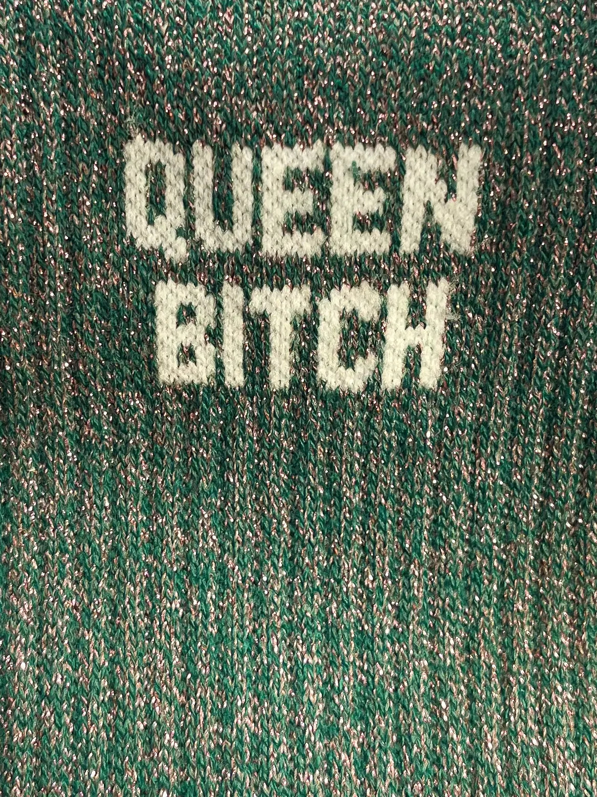 Focus sur la chaussette Félicie cousue en coton, verte à paillettes avec « Queen Bitch » écris en blanc