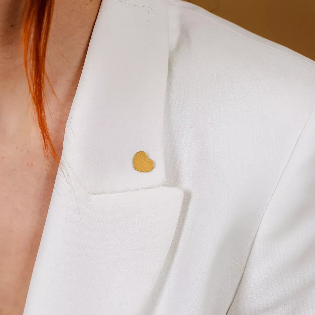 Pins Bisou doré sur une veste blanche