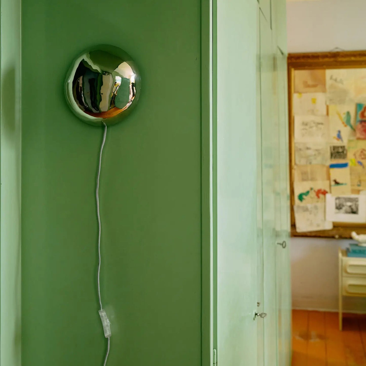 L'applique Orb accrochée sur un mur vert
