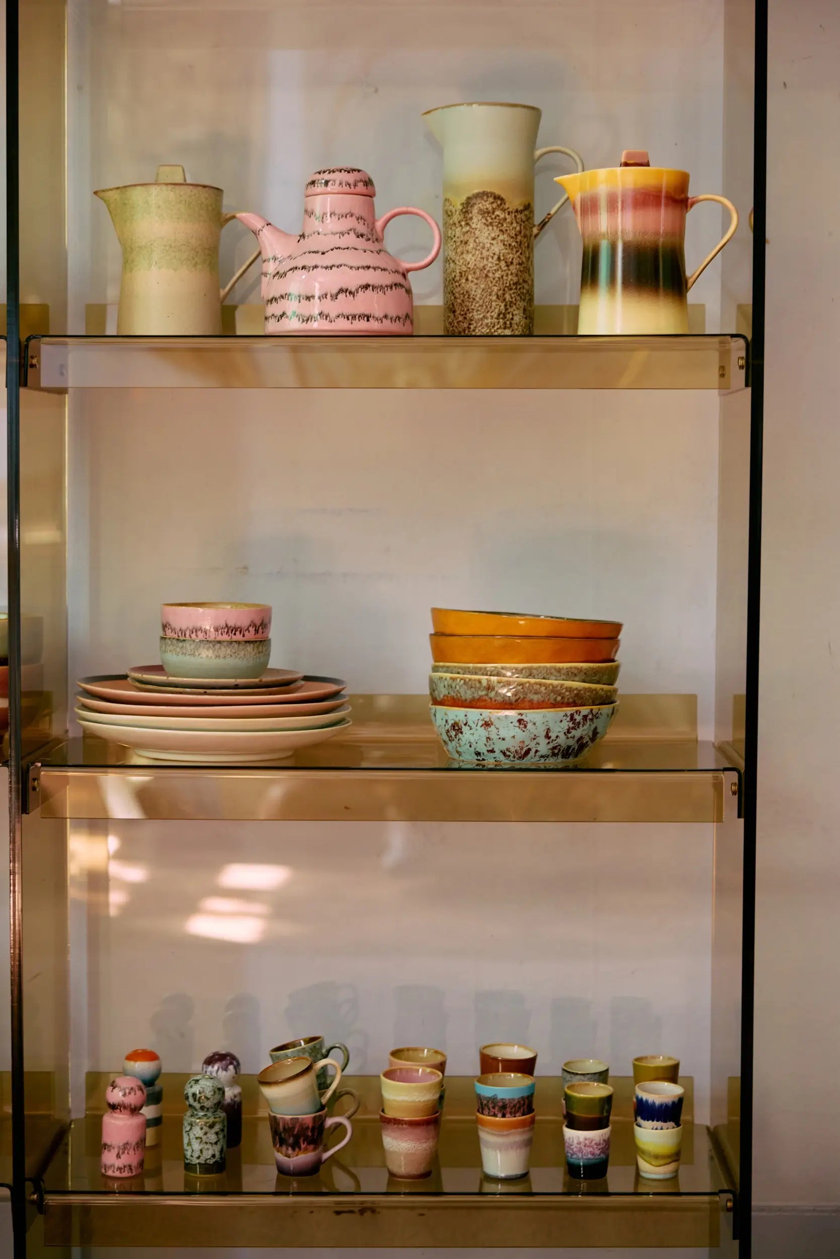 Vaisselle en céramique HK living sur des étagères en verre