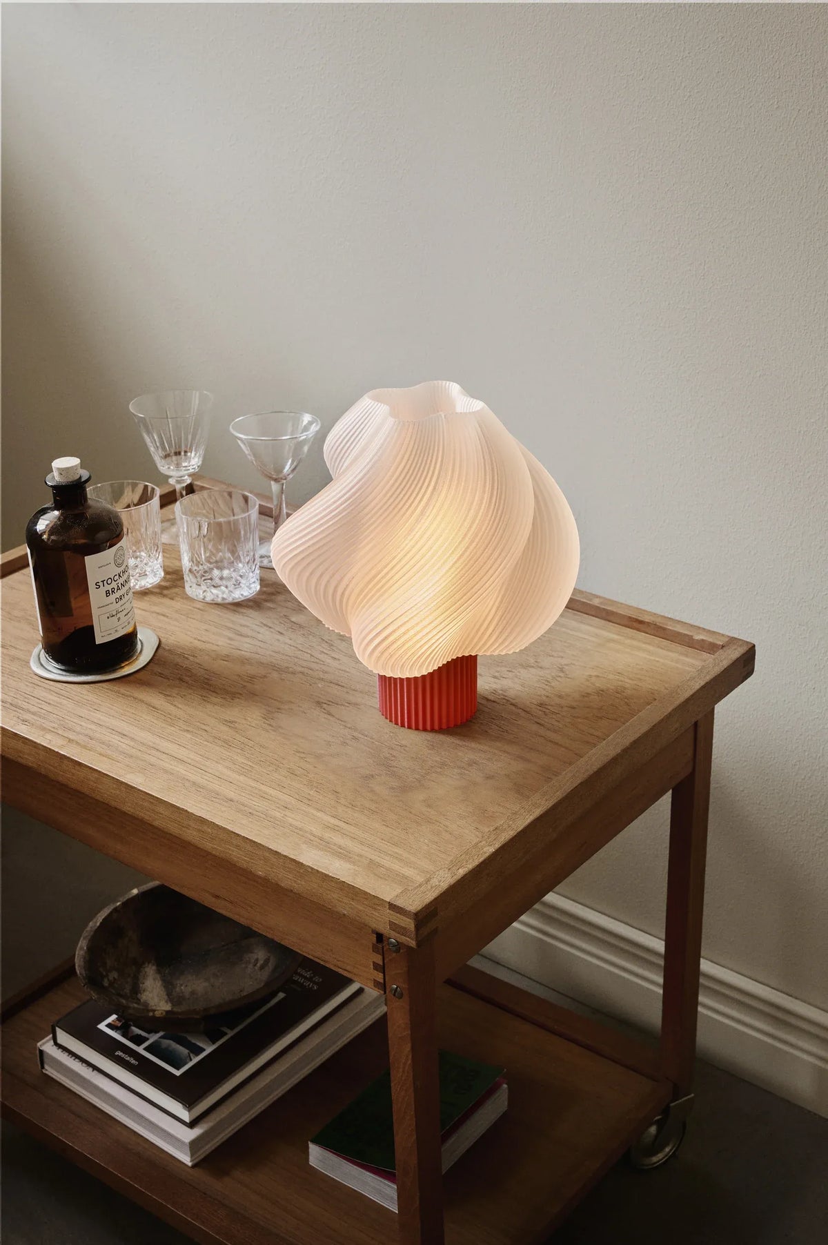 Lampe de table Soft Serve Rhubarbe allumée sur une table en bois