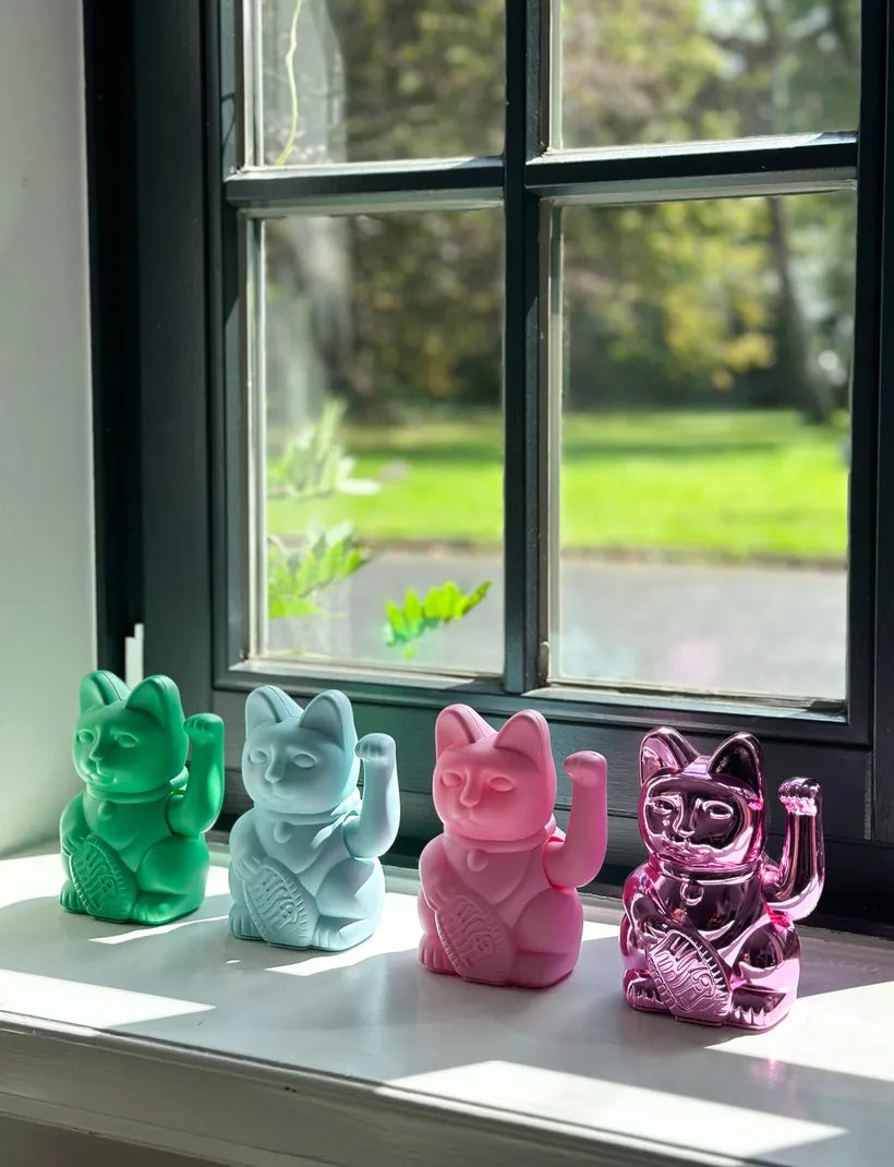 Maneki Neko Donkey bleu clair, vert vif, rose vif et rose brillant sur un rebord de fenêtre