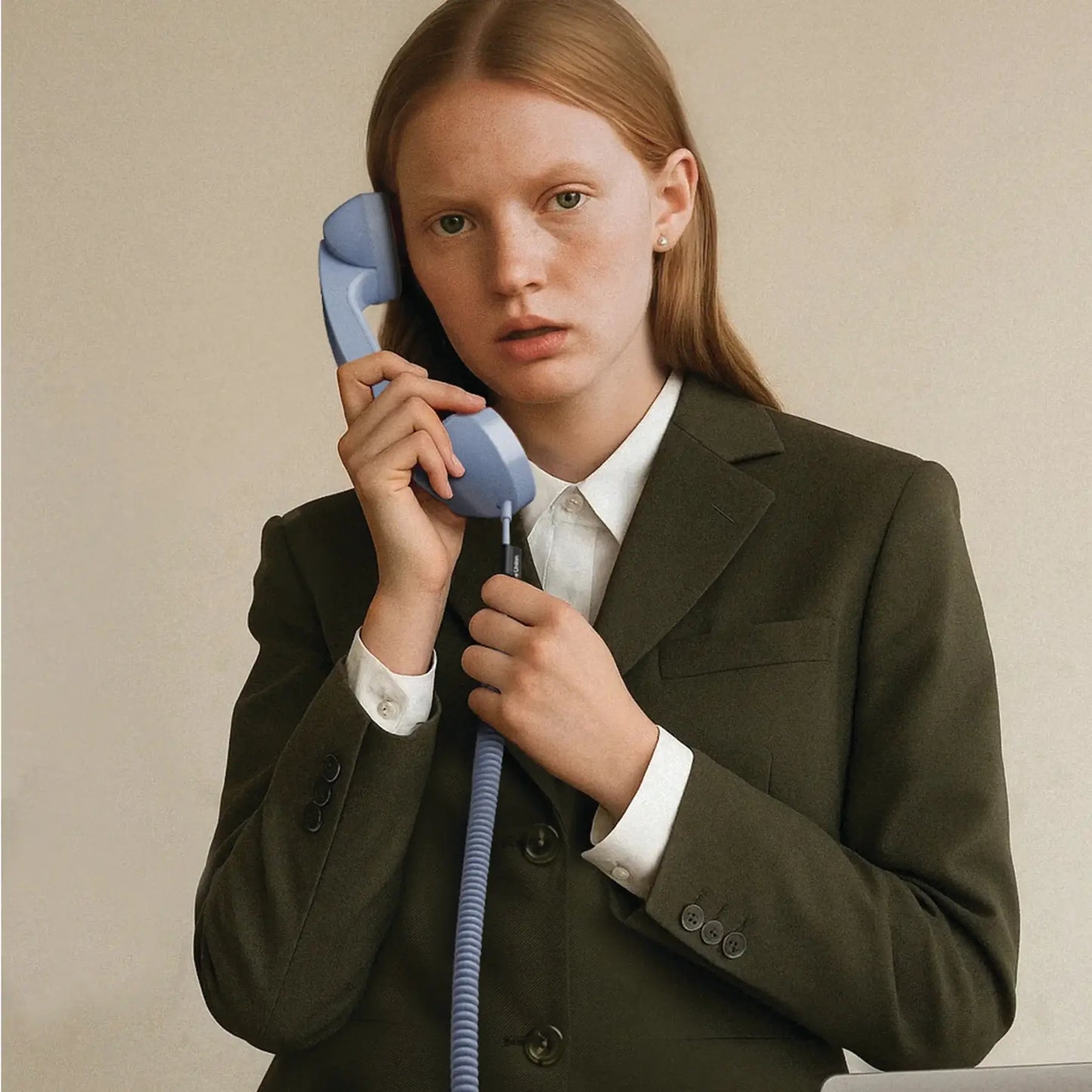 Utilisation du combiné Pop Phone de couleur Azur par une jeune femme en costume.