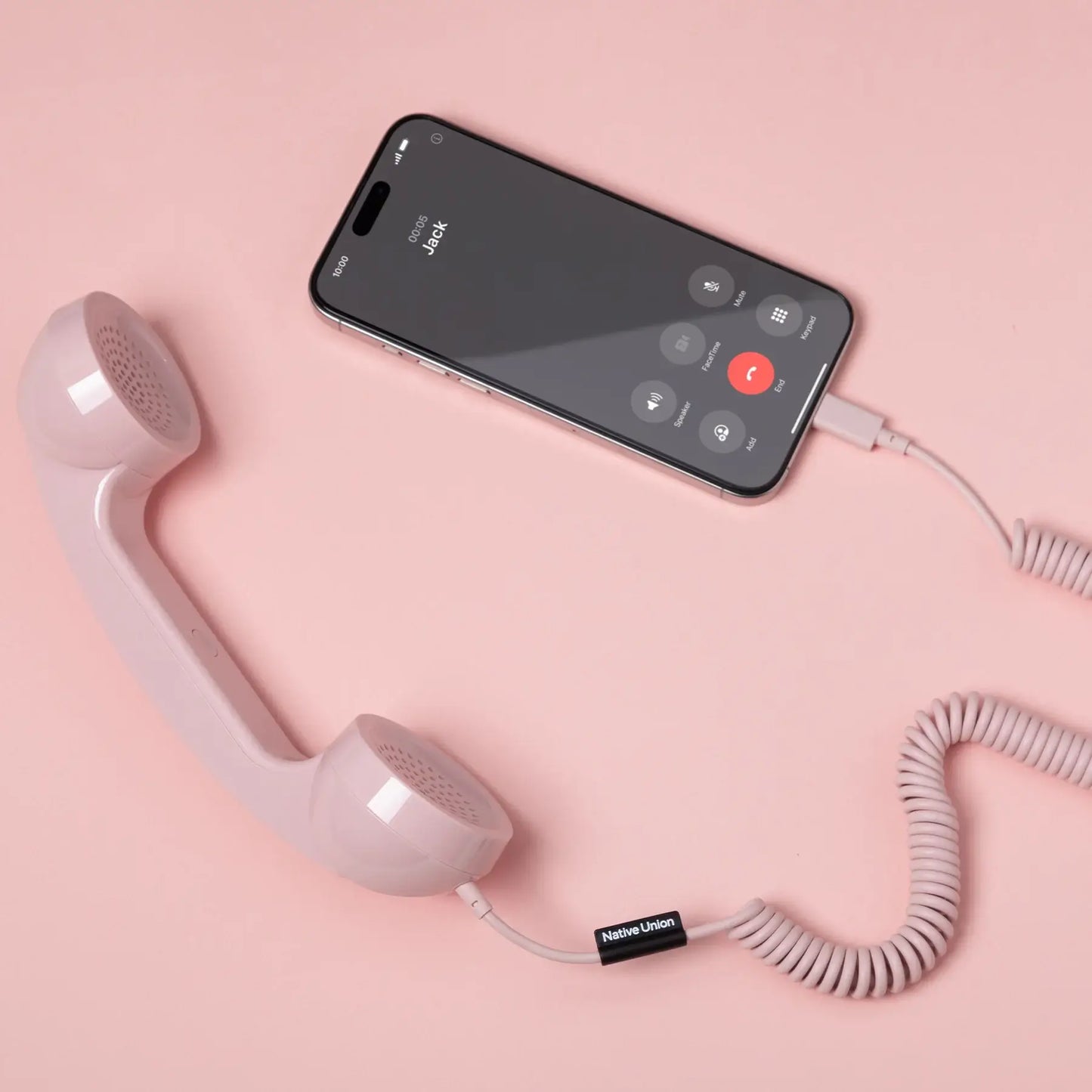 Combiné de téléphone Pop Phone Rose Bonbon de chez Native Union, relié à un smartphone avec un câble USB-C.