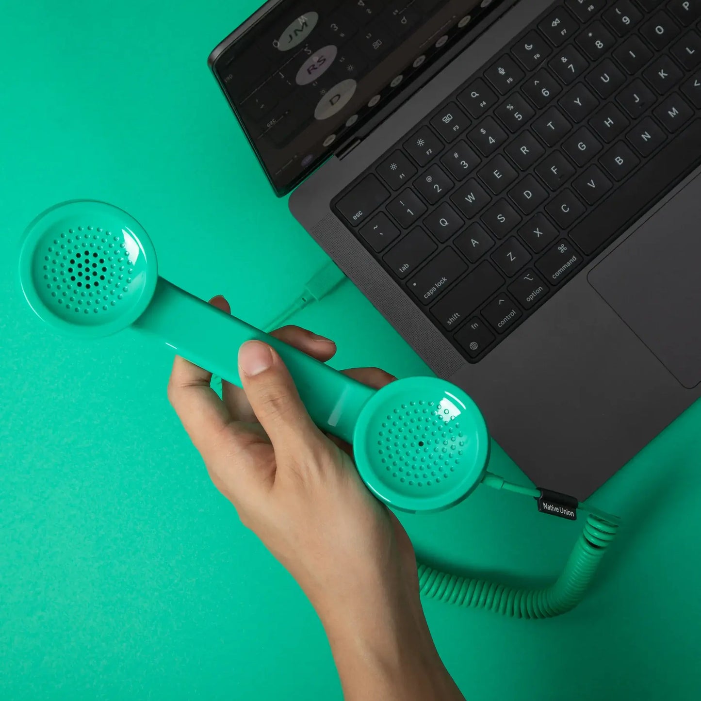 Combiné de téléphone Pop Phone Vert Pin de chez Native Union, branché à un ordinateur avec un câble USB-C.