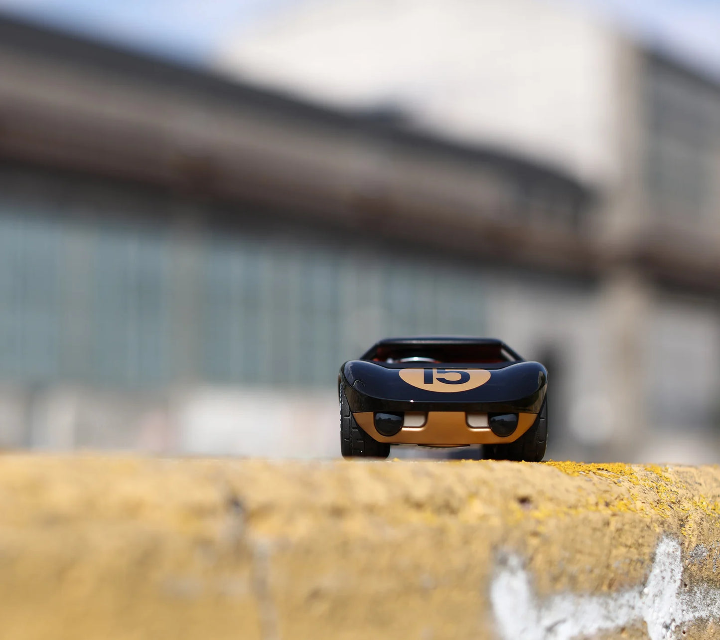 Voiture miniature Playforever Ken Cave noire et or dans un environnement industriel