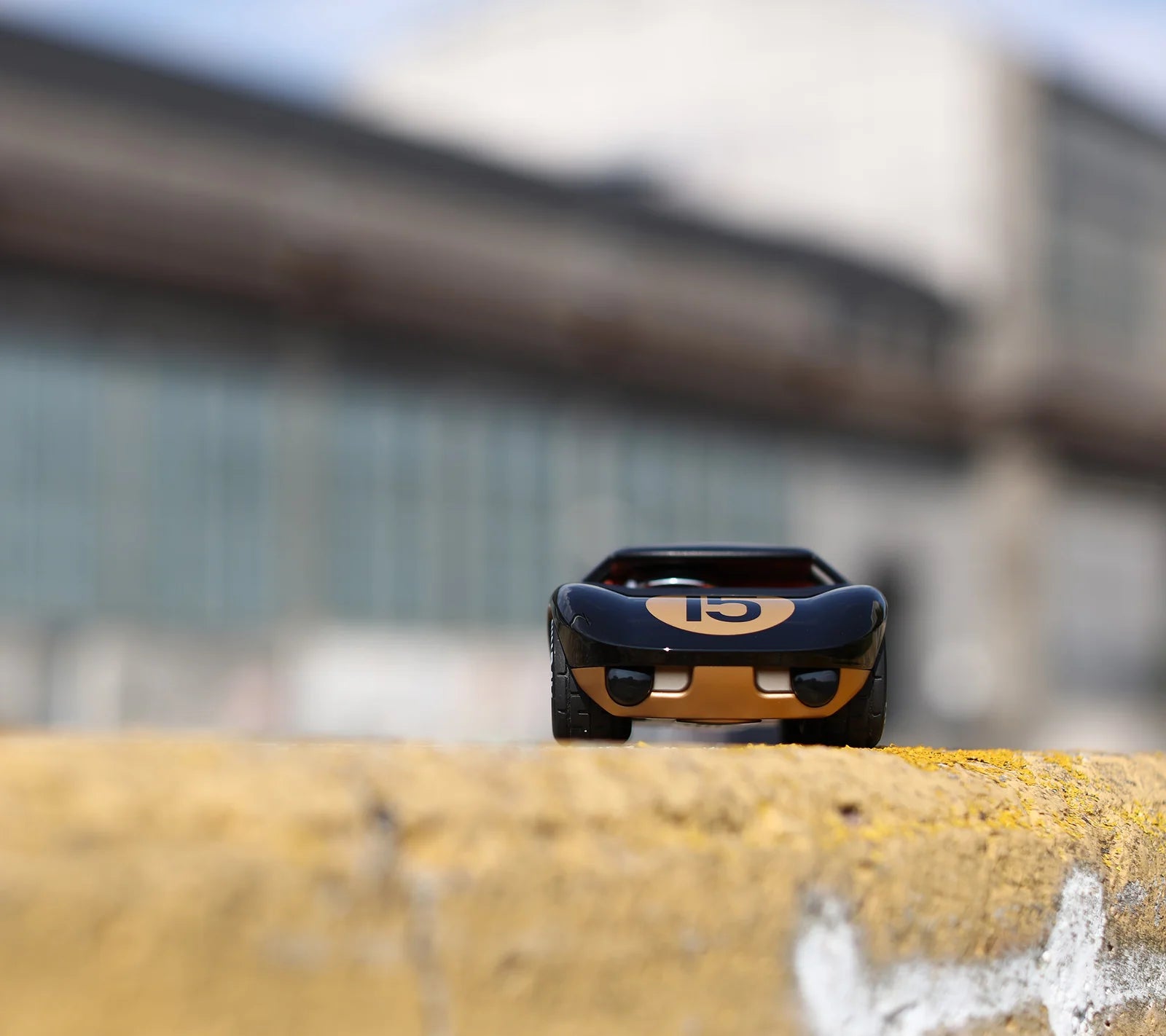 Voiture miniature Playforever Ken Cave noire et or dans un environnement industriel