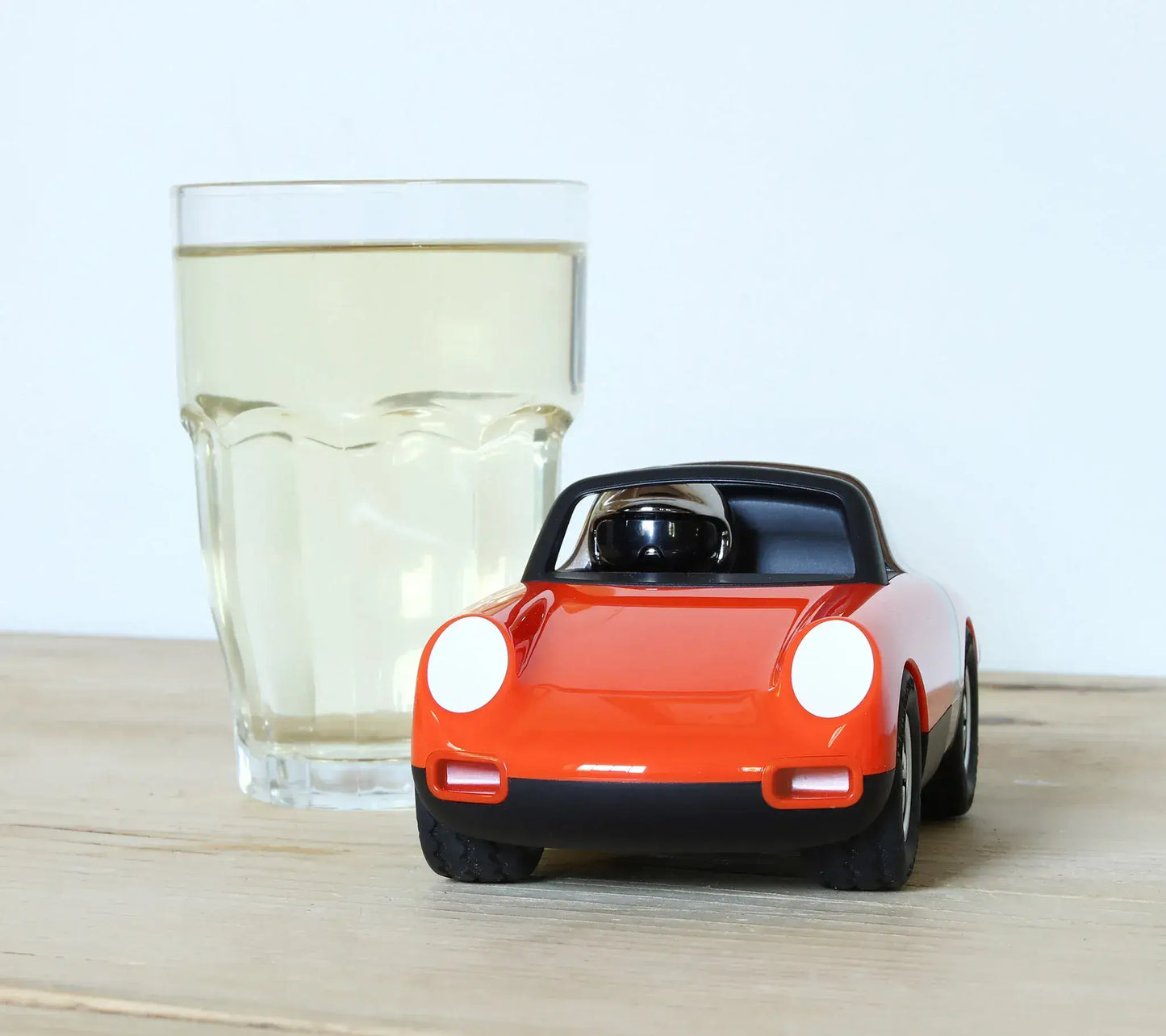Voiture miniature Playforever Luft Biba orange présentée à côté d'un verre pour illustrer sa taille