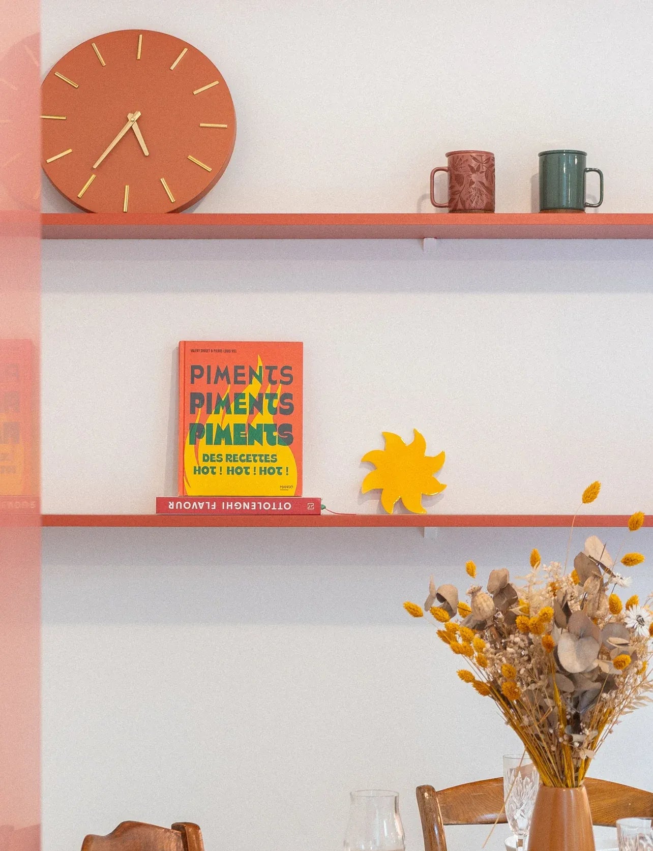 Soleil mural jaune en céramique Maison Béata sur une étagère rouge