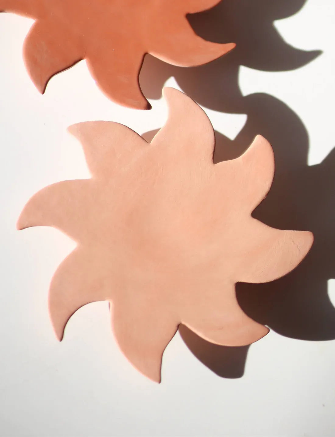 Détail de la matière mate du soleil mural Terracotta brute à côté de terracotta émaillé