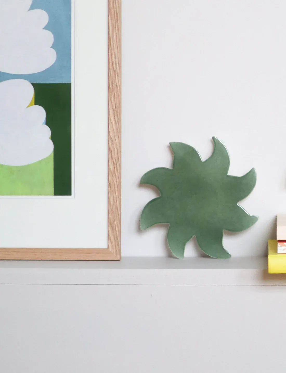 Soleil mural vert en céramique Maison Béata posé sur une étagère